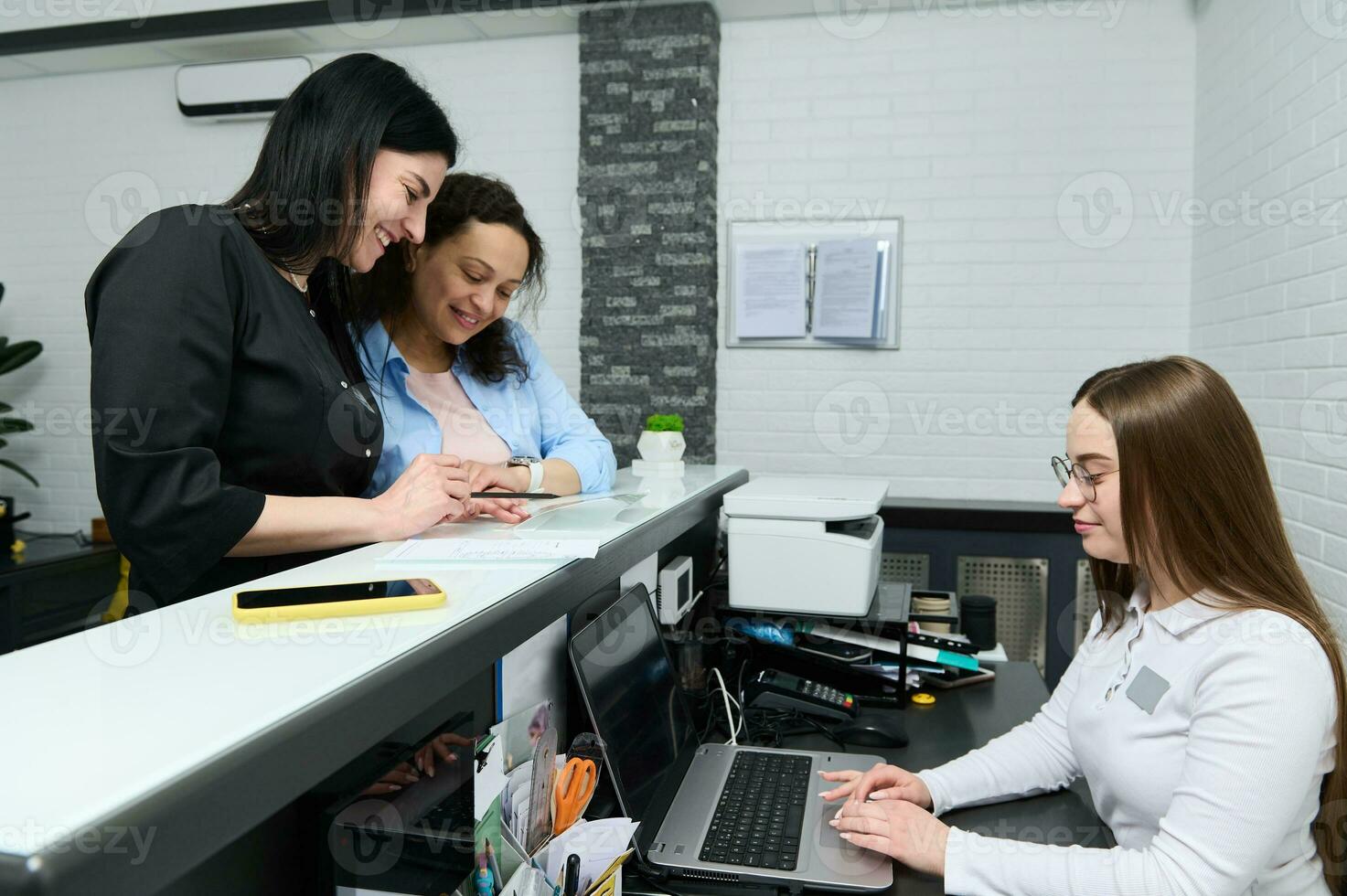 hembra médico y paciente relleno fuera y firma formularios, en pie a el recepción mostrador en un moderno médico clínica foto