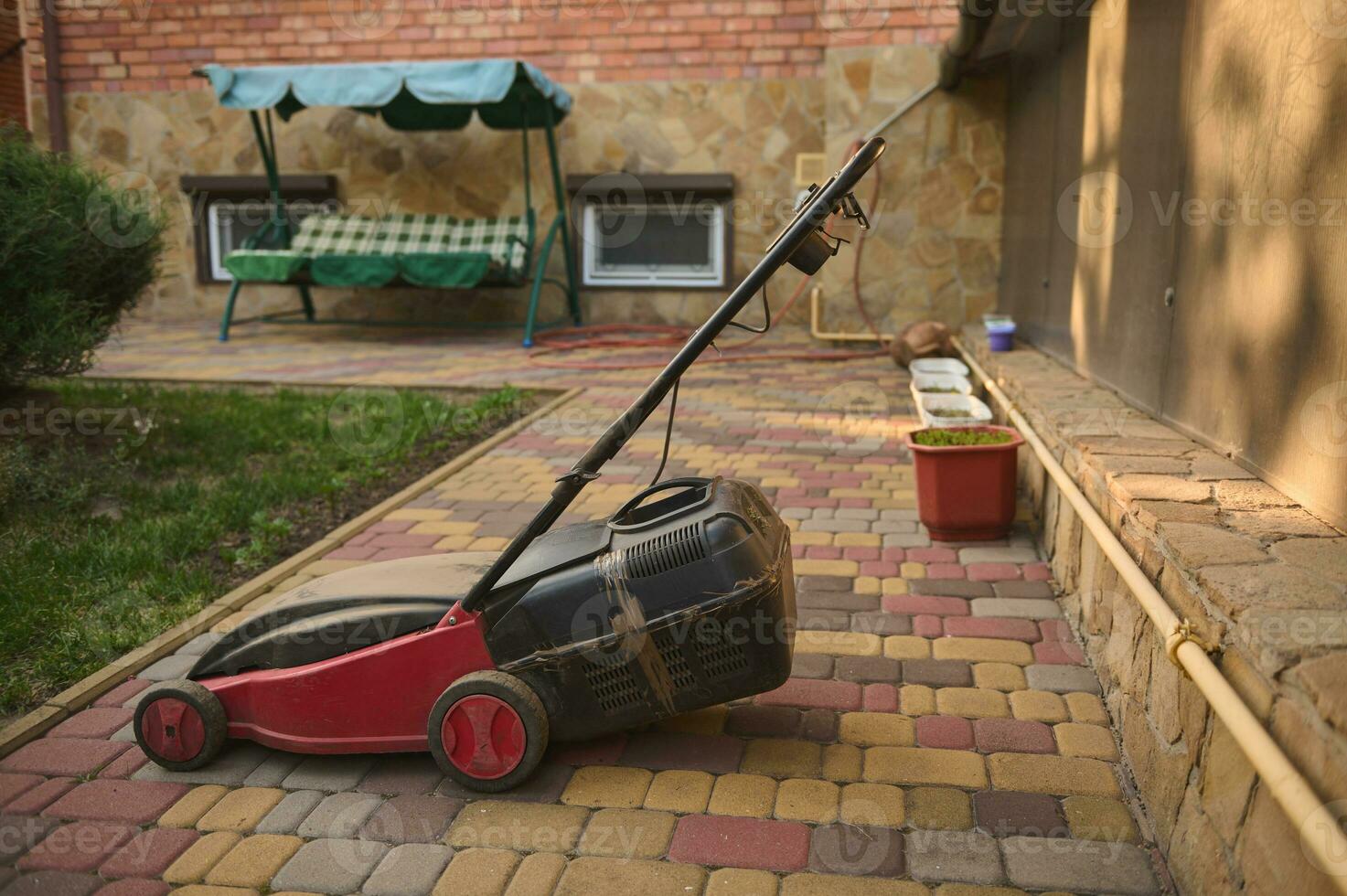 Old electric lawn mower on pavement in a backyard. Landscaping industry and garden maintenance concept. Still life. photo