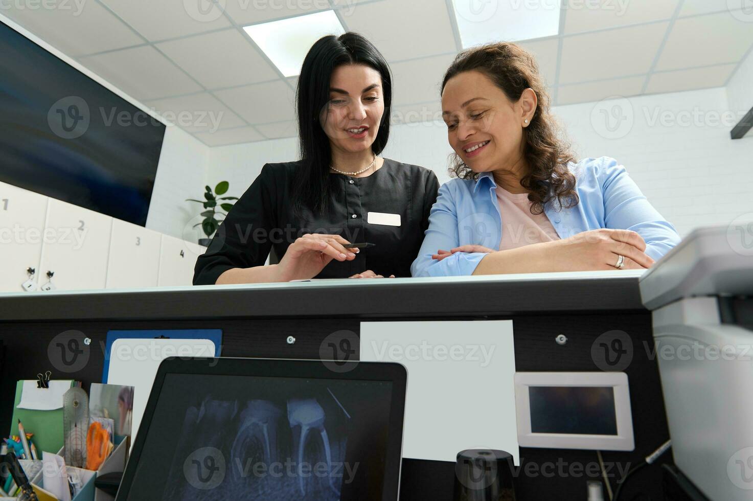 Confident experienced dentist prescribing to her patient the dental treatment that needs to perform in dentistry clinic photo