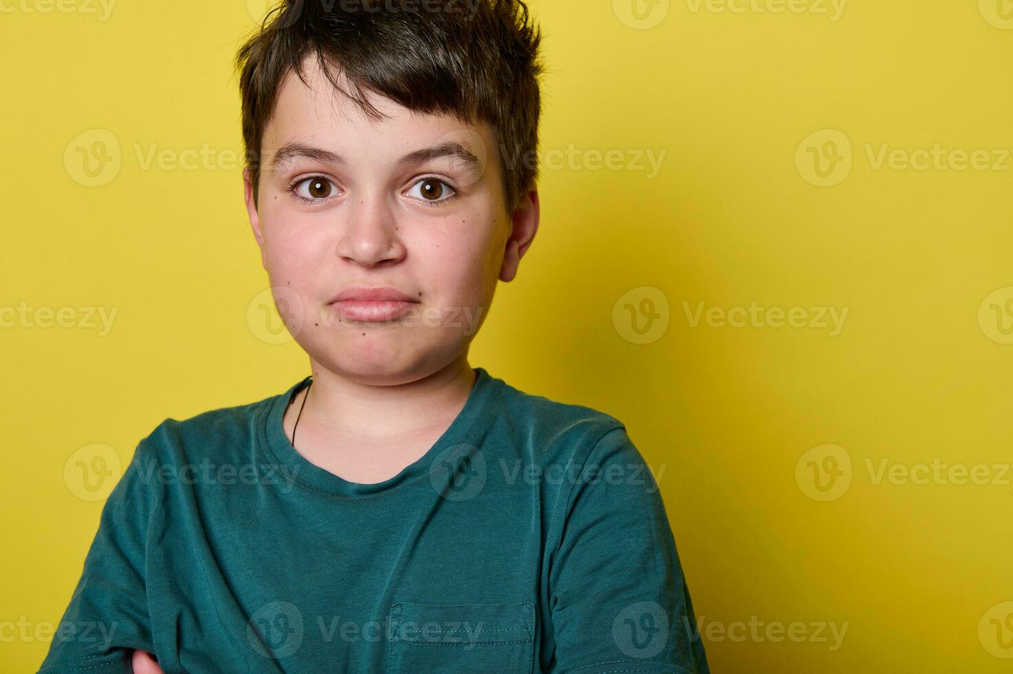 Headshot. Caucasian handsome mischievous teen boy, teenager, school kid smiling looking at camera, isolated on yellow photo