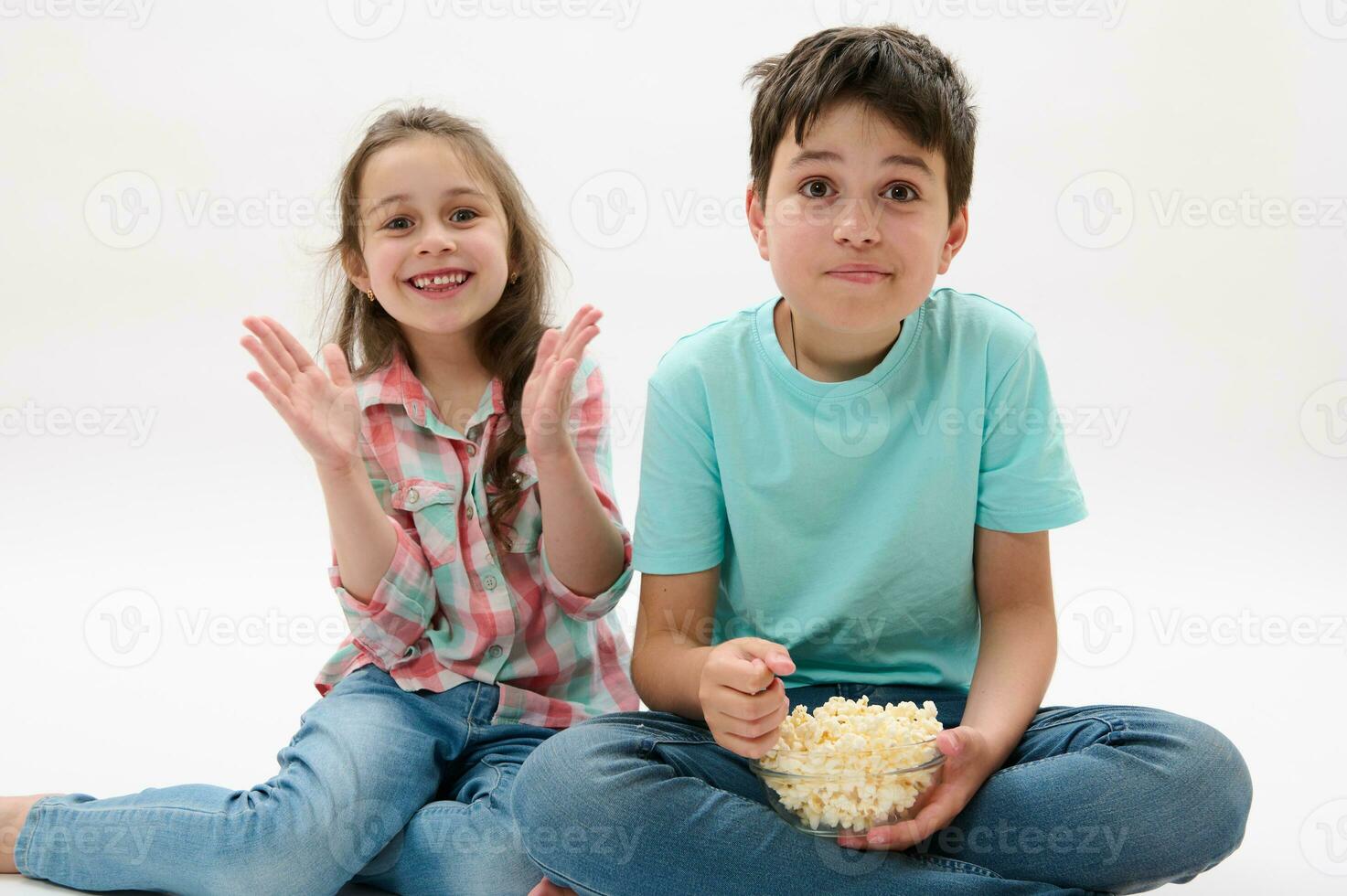 Portrait on white background of happy beautiful kids, boy and girl, brother and sister eating popcorn, on white backdrop photo