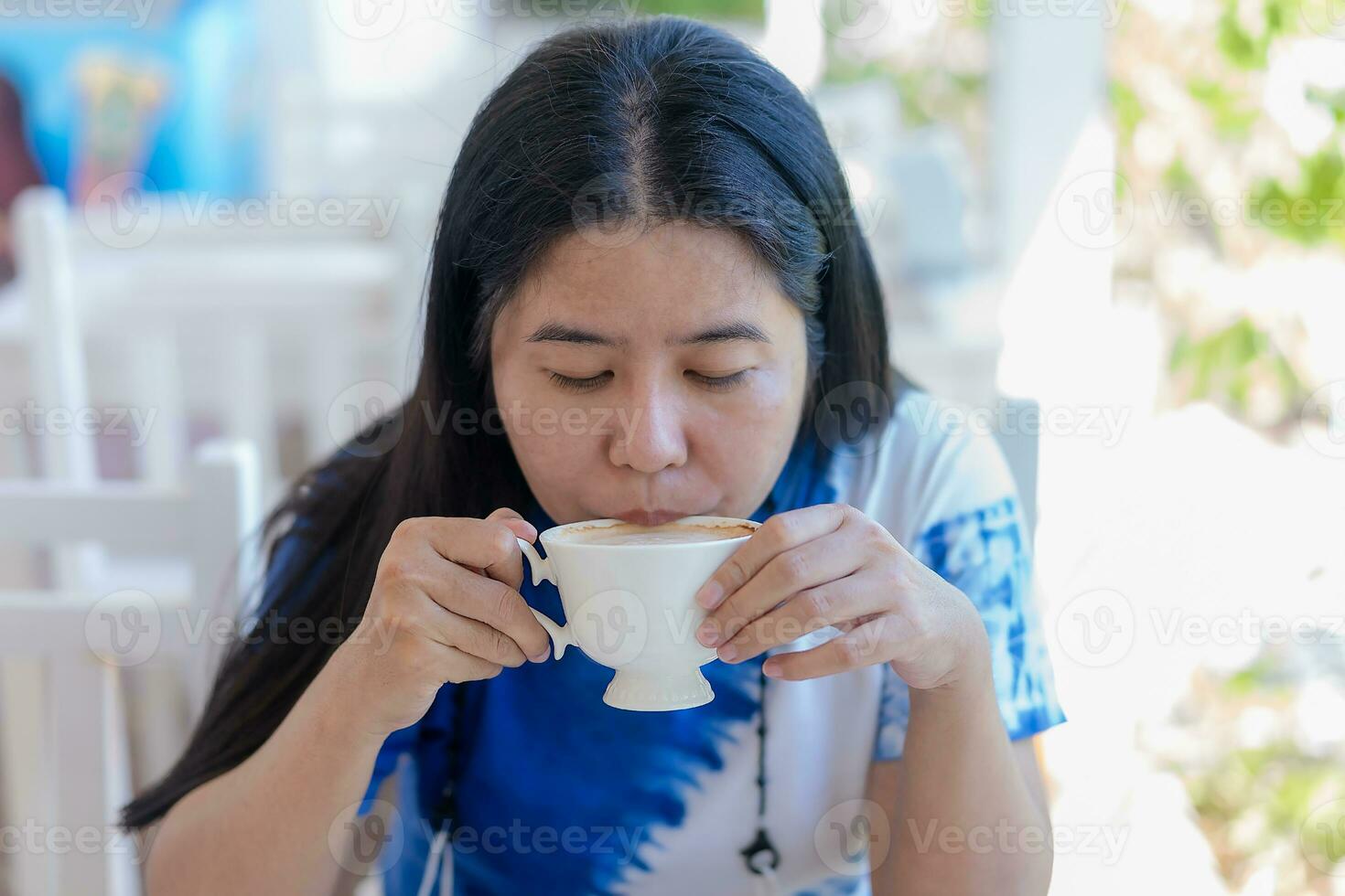 Asian middle woman relaxing on table with coffee at restuarant or cafe. Woman drinking coffee in the morning. photo