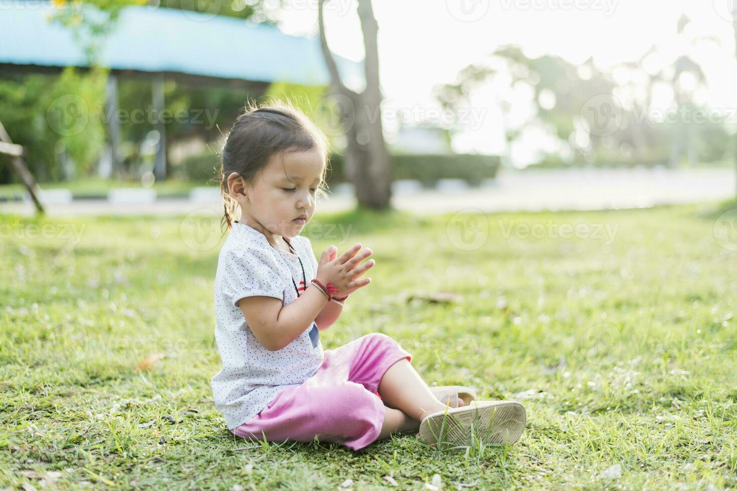 Little asian girl practicing mindfulness meditation outdoor in a park. photo