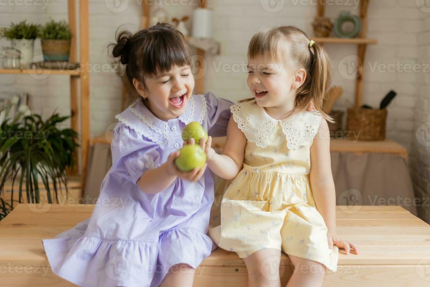 little happy girls fool around in the kitchen and eat apples photo