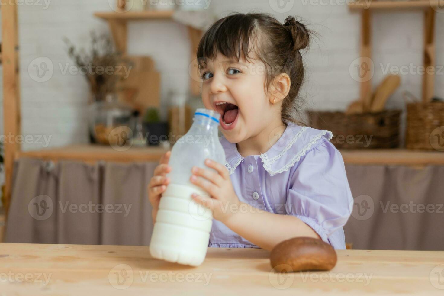 a little beautiful girl in a bright dress is fooling around in the kitchen photo
