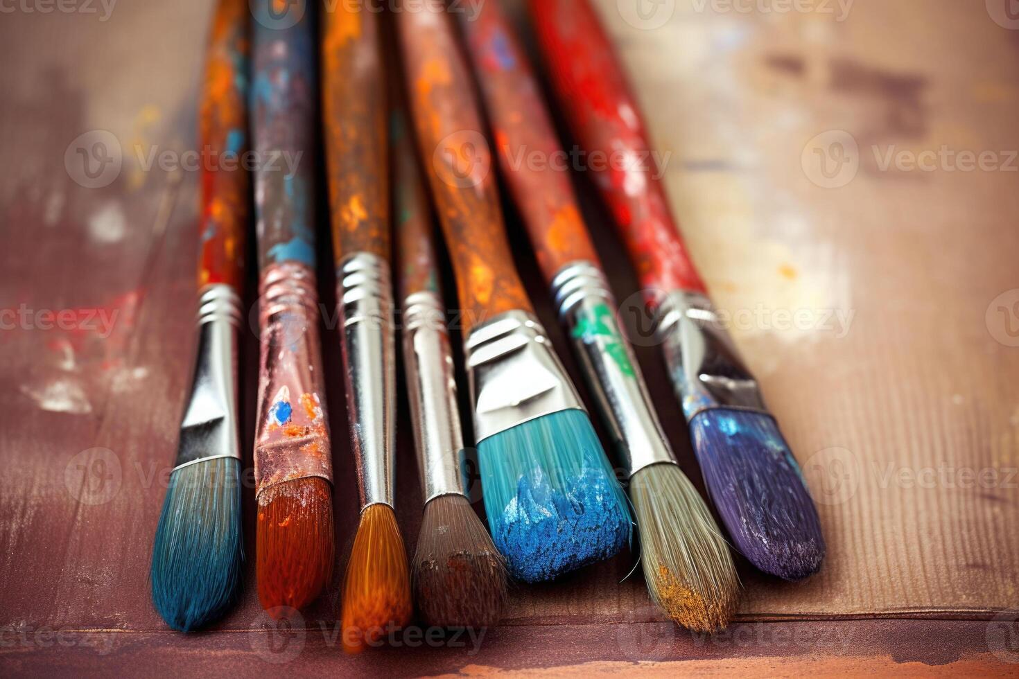 Row of used paintbrushes closeup on wooden background. Brushes with colorful paints. photo