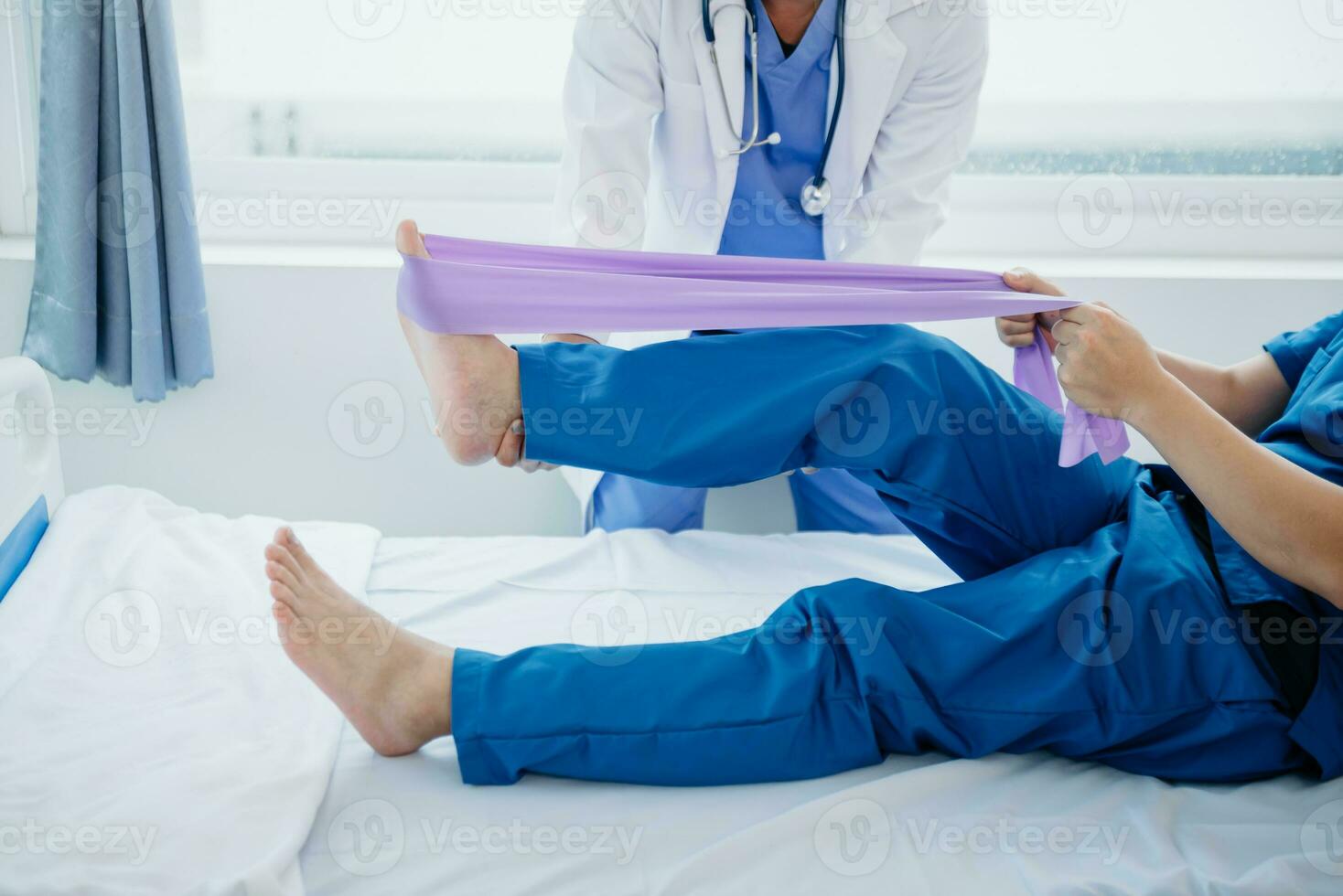 Physiotherapist Helping Patient While Stretching His Leg in bed in clinic photo