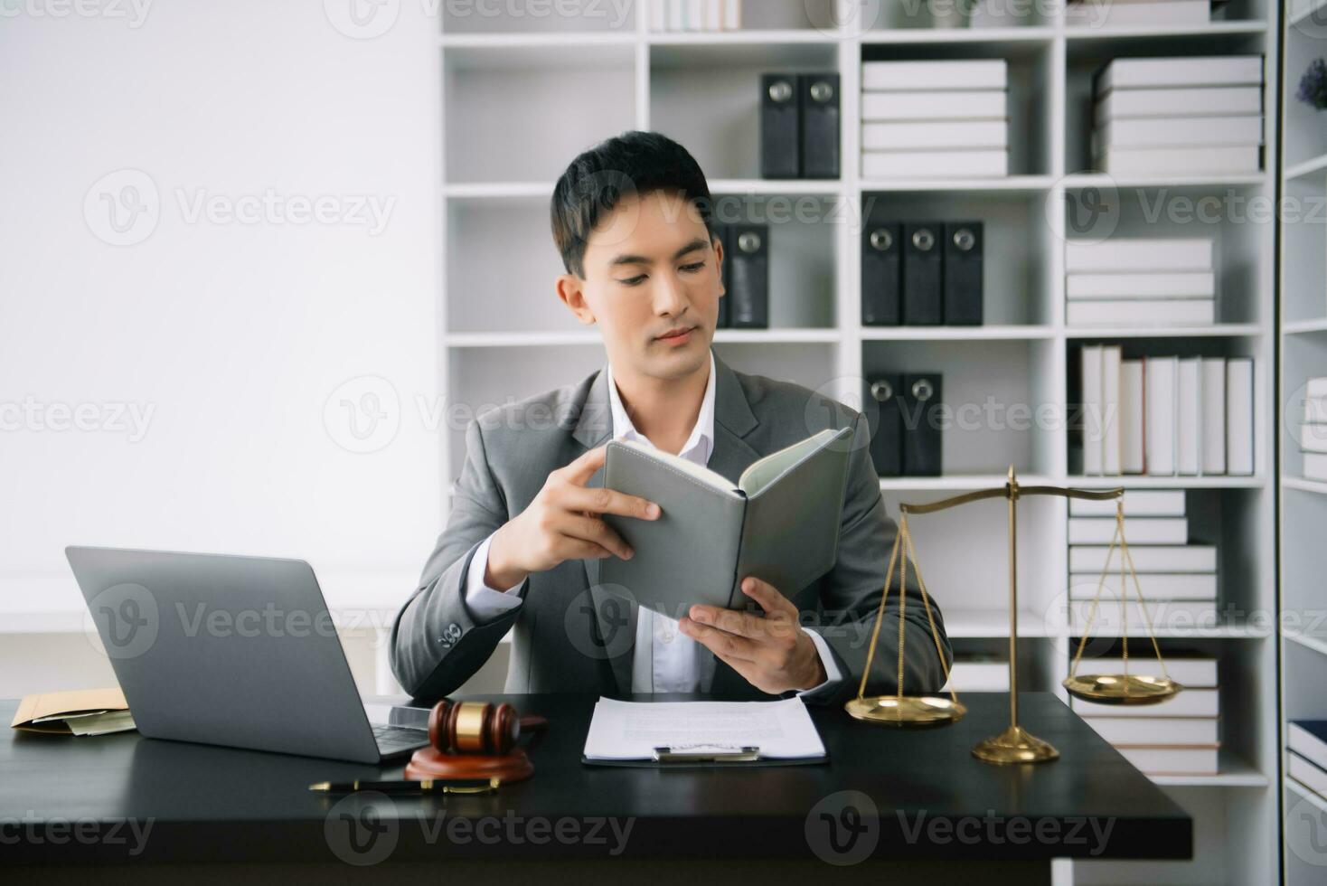 Asian man lawyer reading legal book with gavel on table in office. justice and law ,attorney concept. photo