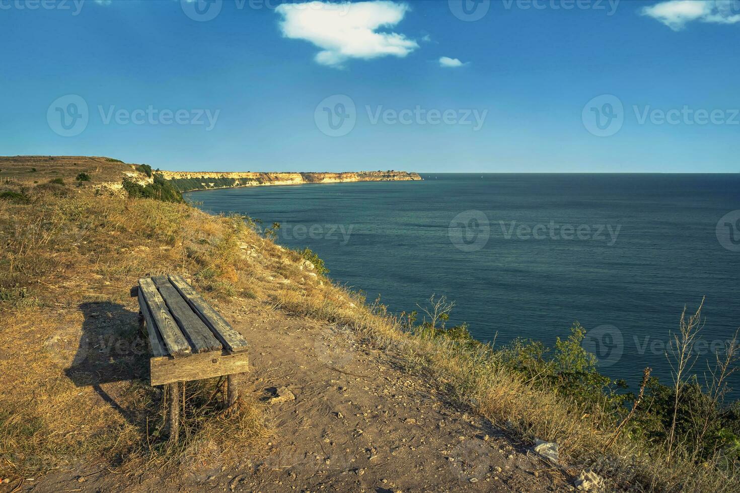 empty bench on the top of sea rocks with a vast view for relaxation photo
