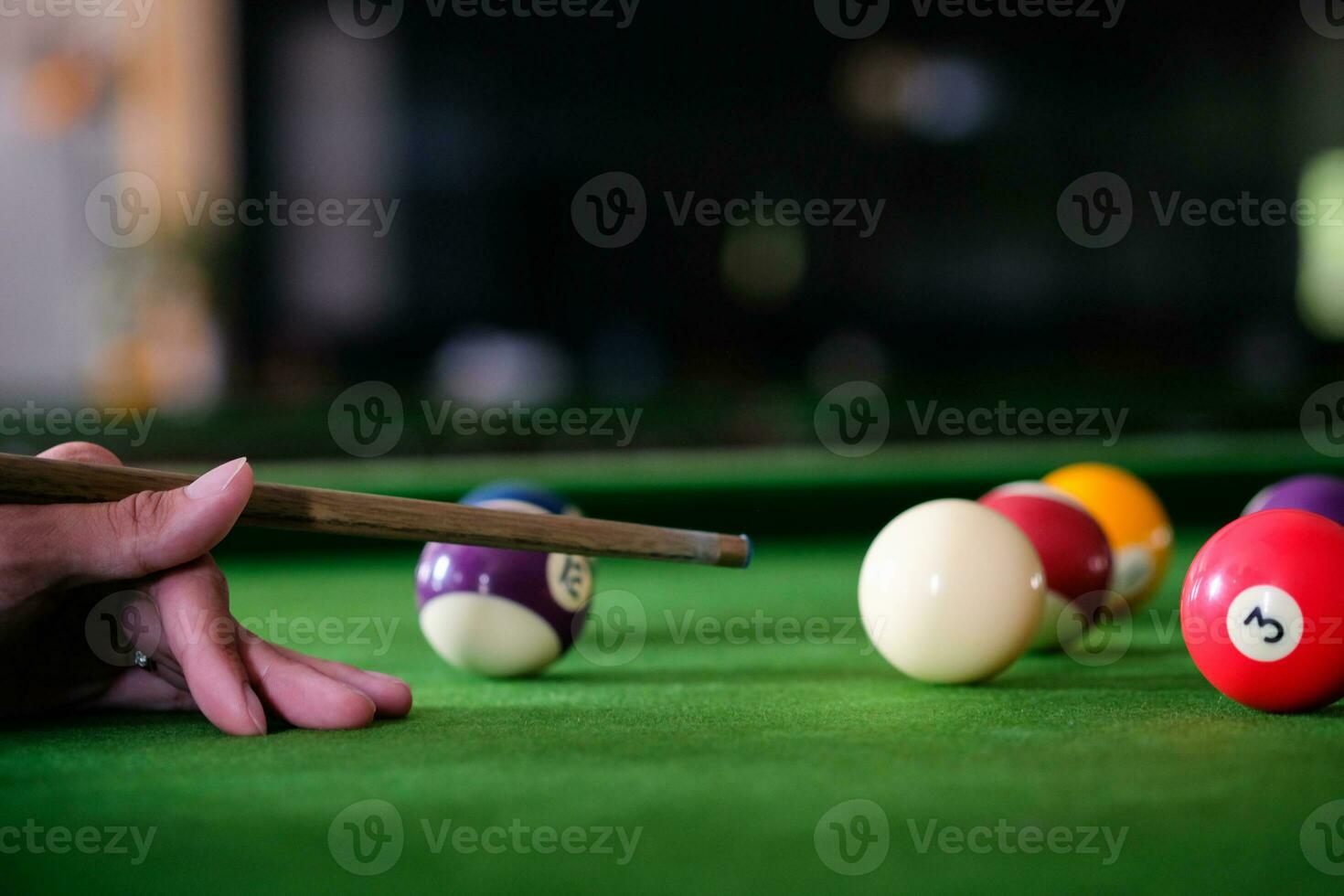 Man's hand and Cue arm playing snooker game or preparing aiming to shoot pool balls on a green billiard table. Colorful snooker balls on green frieze. photo