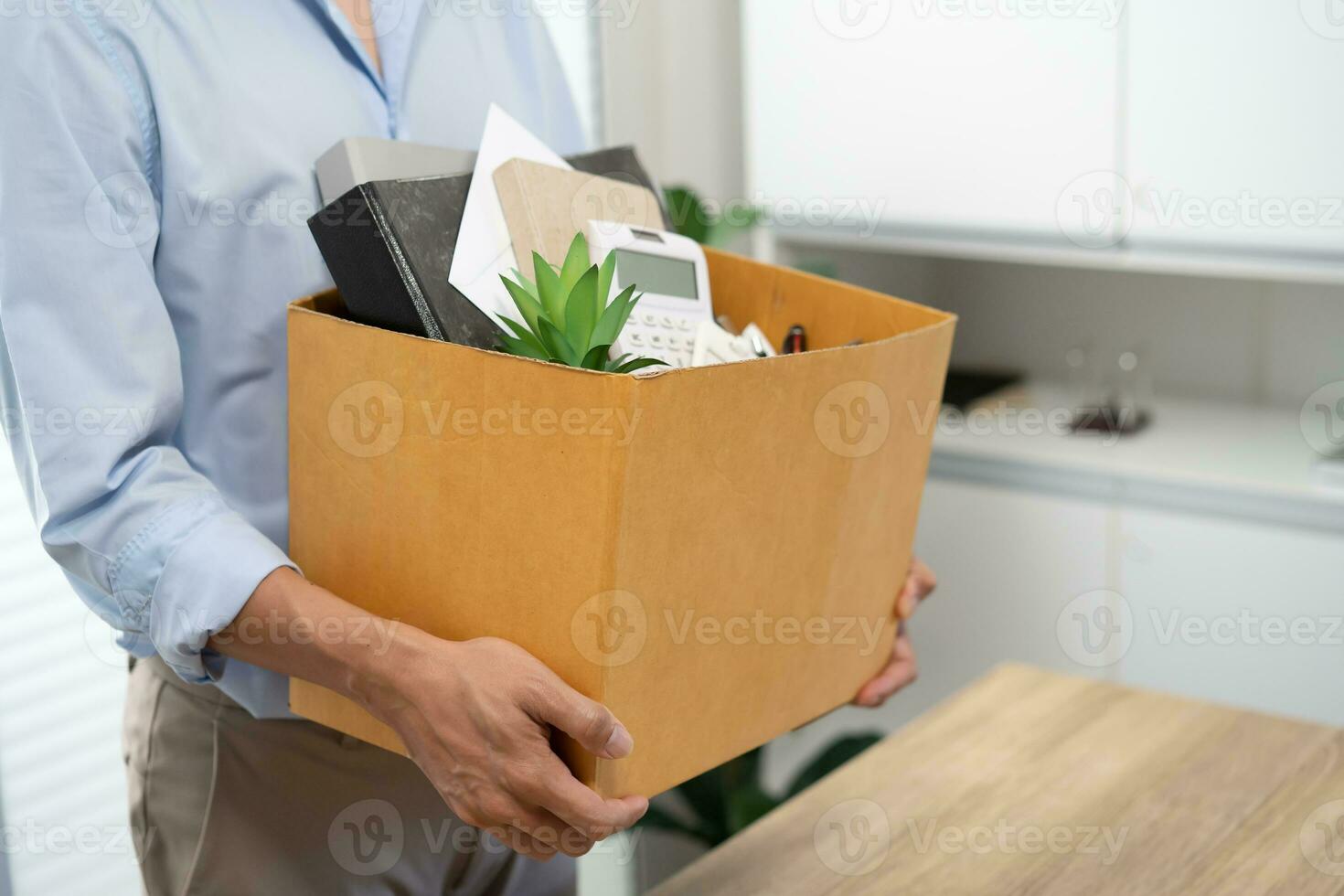 Business man sending resignation letter and packing Stuff Resign Depress or carrying business cardboard box by desk in office. Change of job or fired from company photo