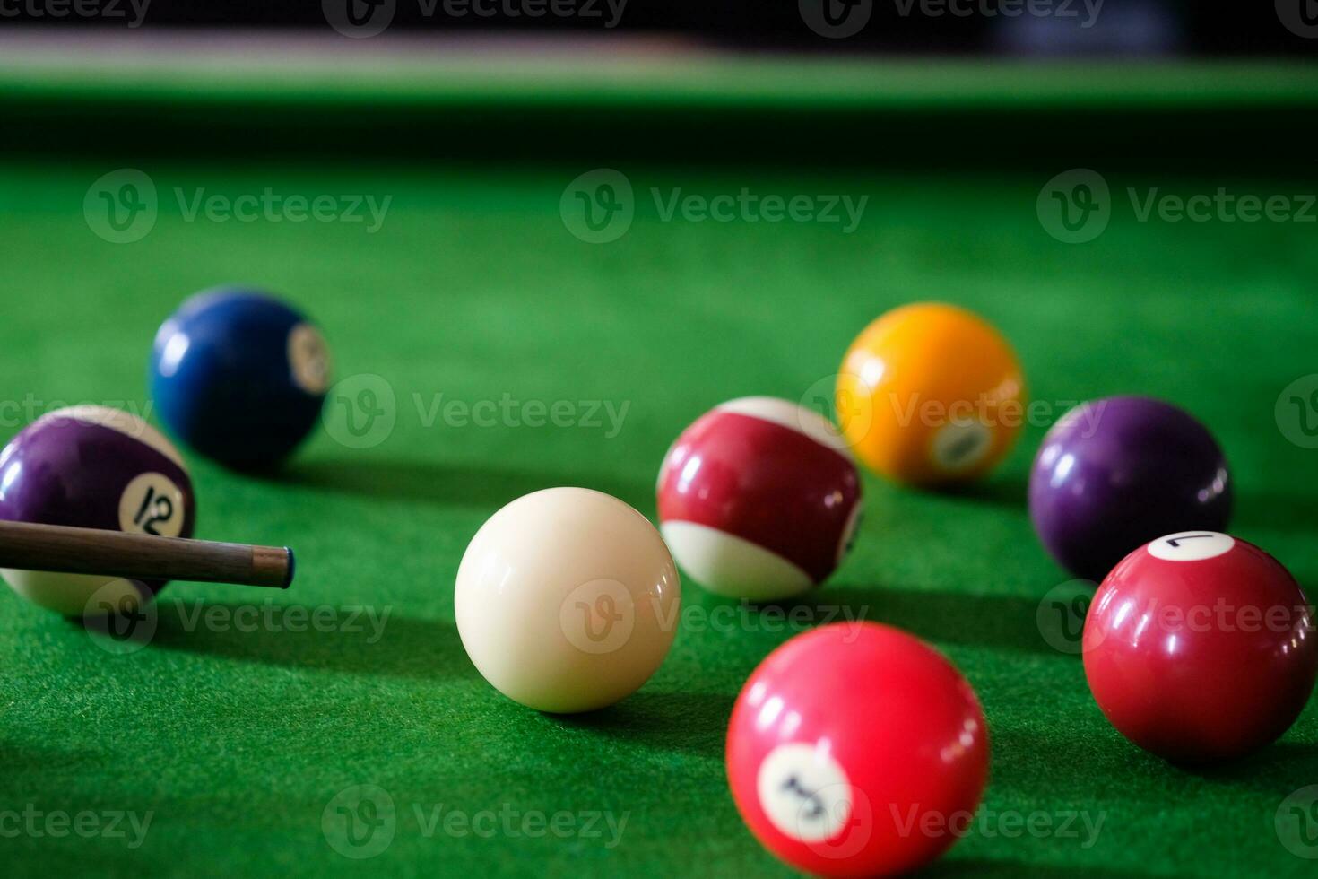 Man's hand and Cue arm playing snooker game or preparing aiming to shoot pool balls on a green billiard table. Colorful snooker balls on green frieze. photo