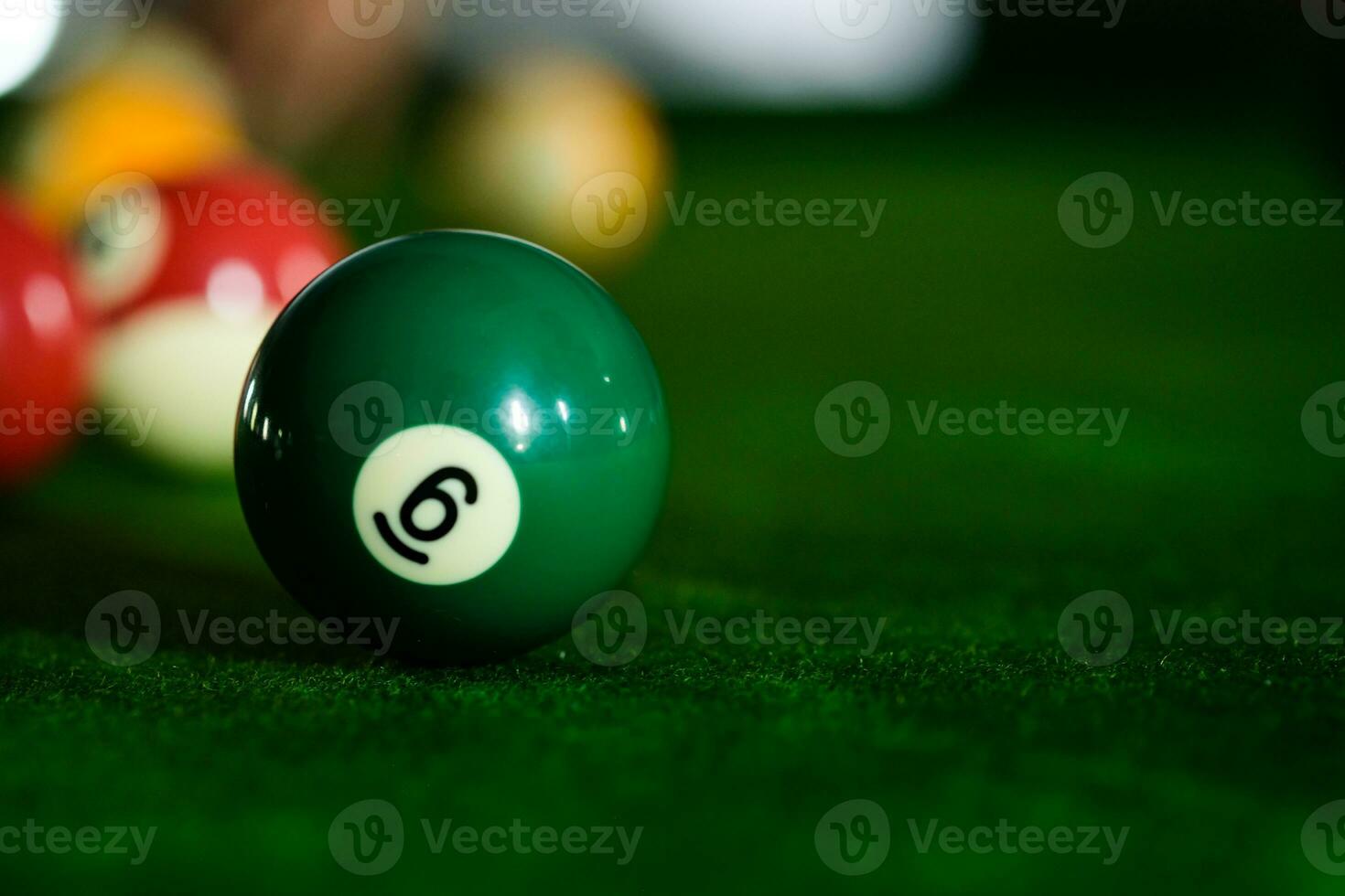 Man's hand and Cue arm playing snooker game or preparing aiming to shoot pool balls on a green billiard table. Colorful snooker balls on green frieze. photo