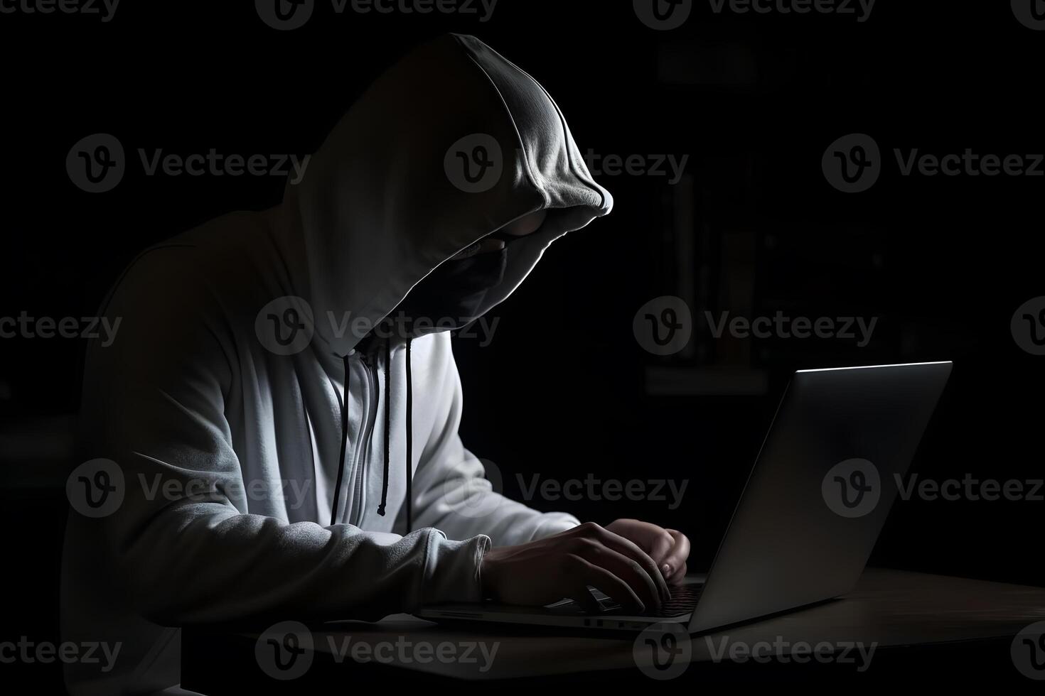 Mysterious hacker wearing a hoodie is typing on a laptop, photo