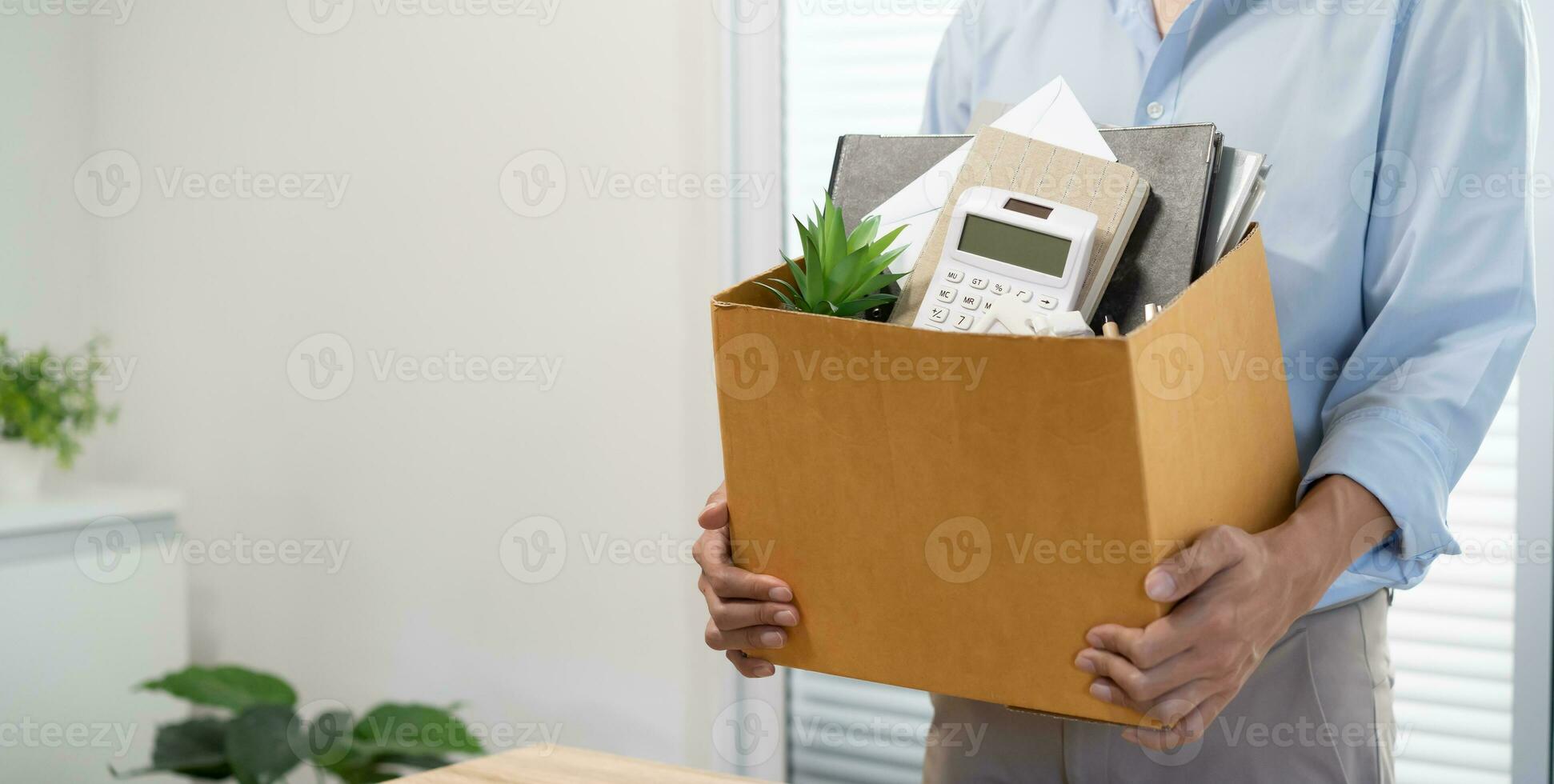 Business man sending resignation letter and packing Stuff Resign Depress or carrying business cardboard box by desk in office. Change of job or fired from company photo
