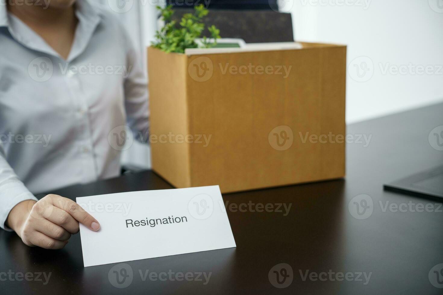 negocio mujer enviando resignación letra a jefe y participación cosas Renunciar deprimir o que lleva cartulina caja por escritorio en oficina foto