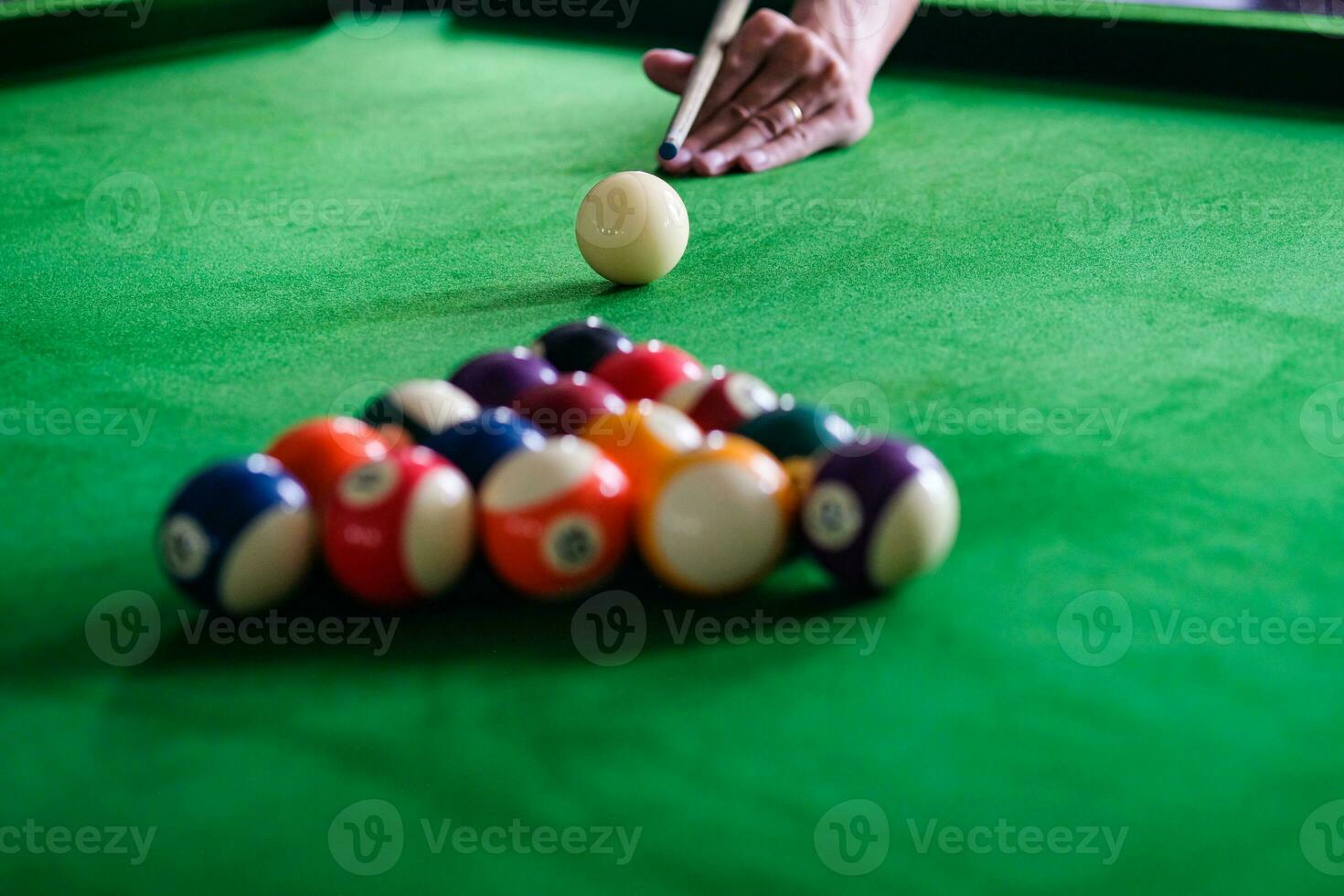 Man's hand and Cue arm playing snooker game or preparing aiming to shoot pool balls on a green billiard table. Colorful snooker balls on green frieze. photo