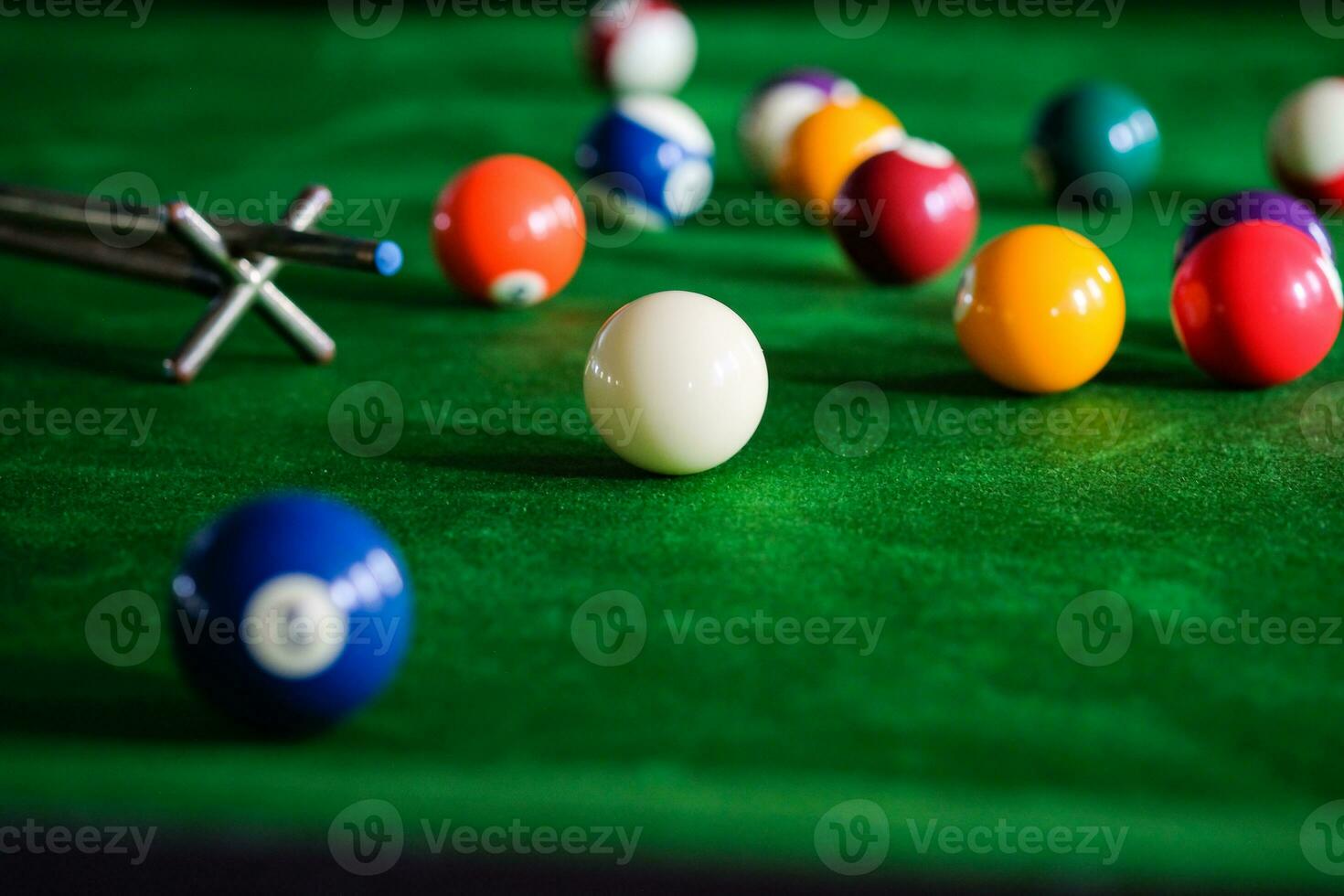 Man's hand and Cue arm playing snooker game or preparing aiming to shoot pool balls on a green billiard table. Colorful snooker balls on green frieze. photo