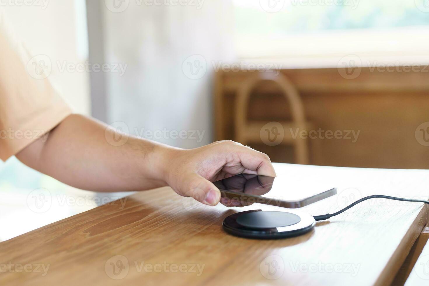 Charging mobile phone battery with wireless charging device in the table. Smartphone charging on a charging pad. Mobile phone near wireless charger Modern lifestyle technology concept. photo