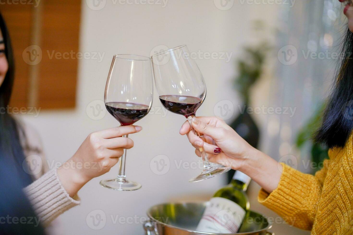 Cheerful friends enjoying home Birthday holiday party. Asian Friends cheering drinking red wine celebrating Christmas or New Year party photo