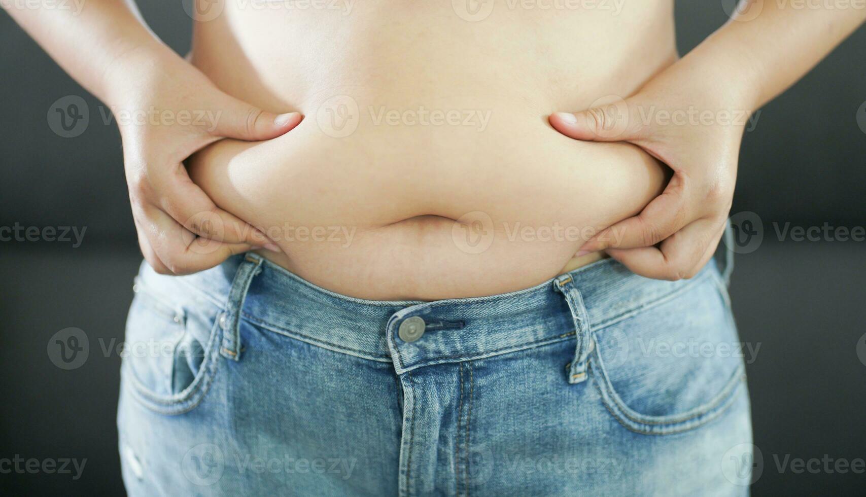 Obese Woman with fat upset about her belly. Overweight woman touching his fat belly and want to lose weight. Fat woman with tight clothing worried about weight diet lifestyle concept photo