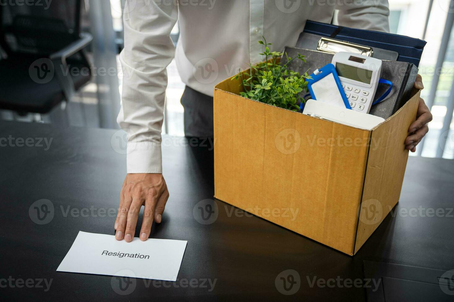 Business man sending resignation letter and packing Stuff Resign Depress or carrying business cardboard box by desk in office. Change of job or fired from company photo