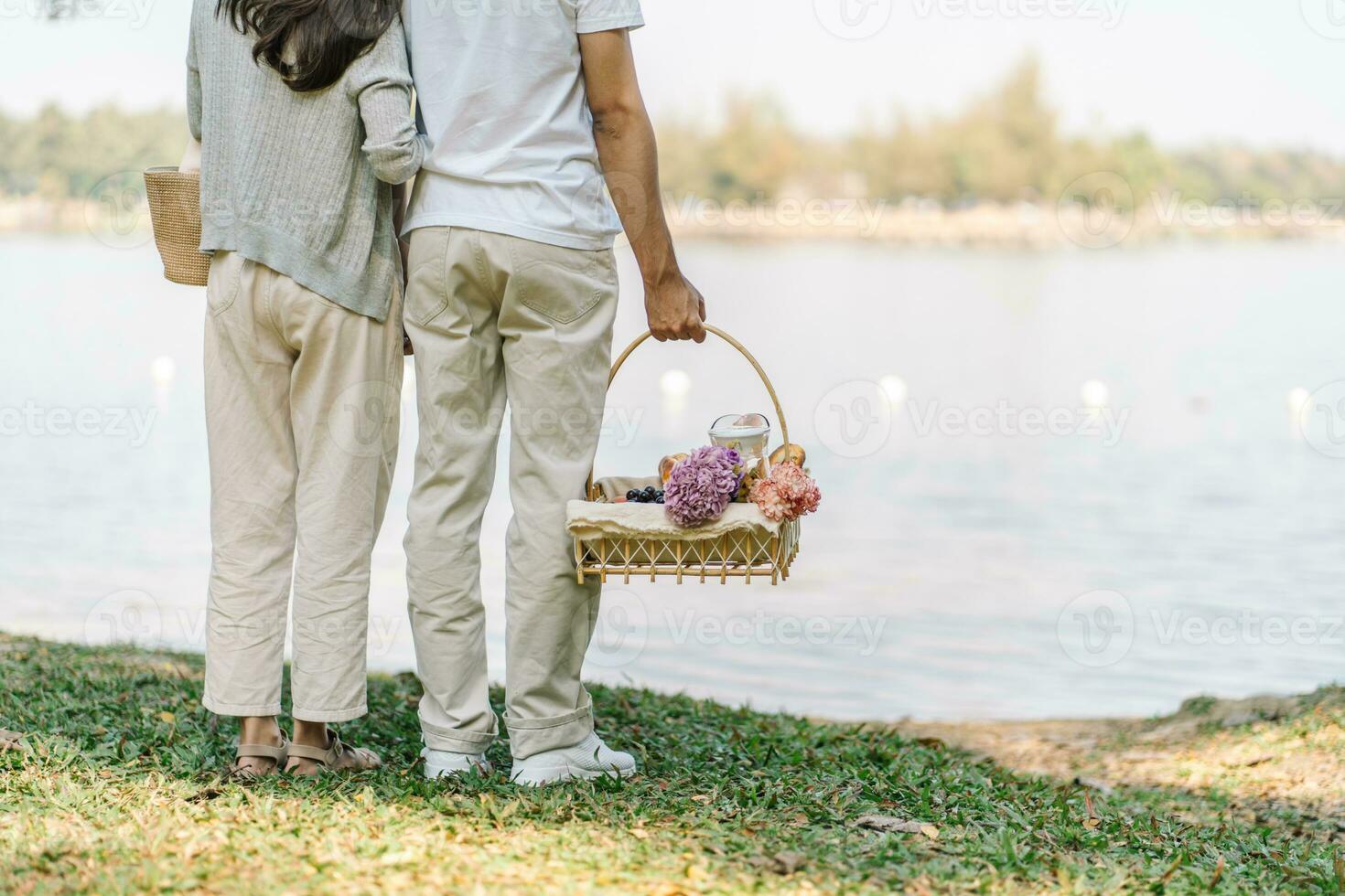 Pareja caminando en jardín con picnic cesta. en amor Pareja es disfrutando picnic hora en parque al aire libre foto