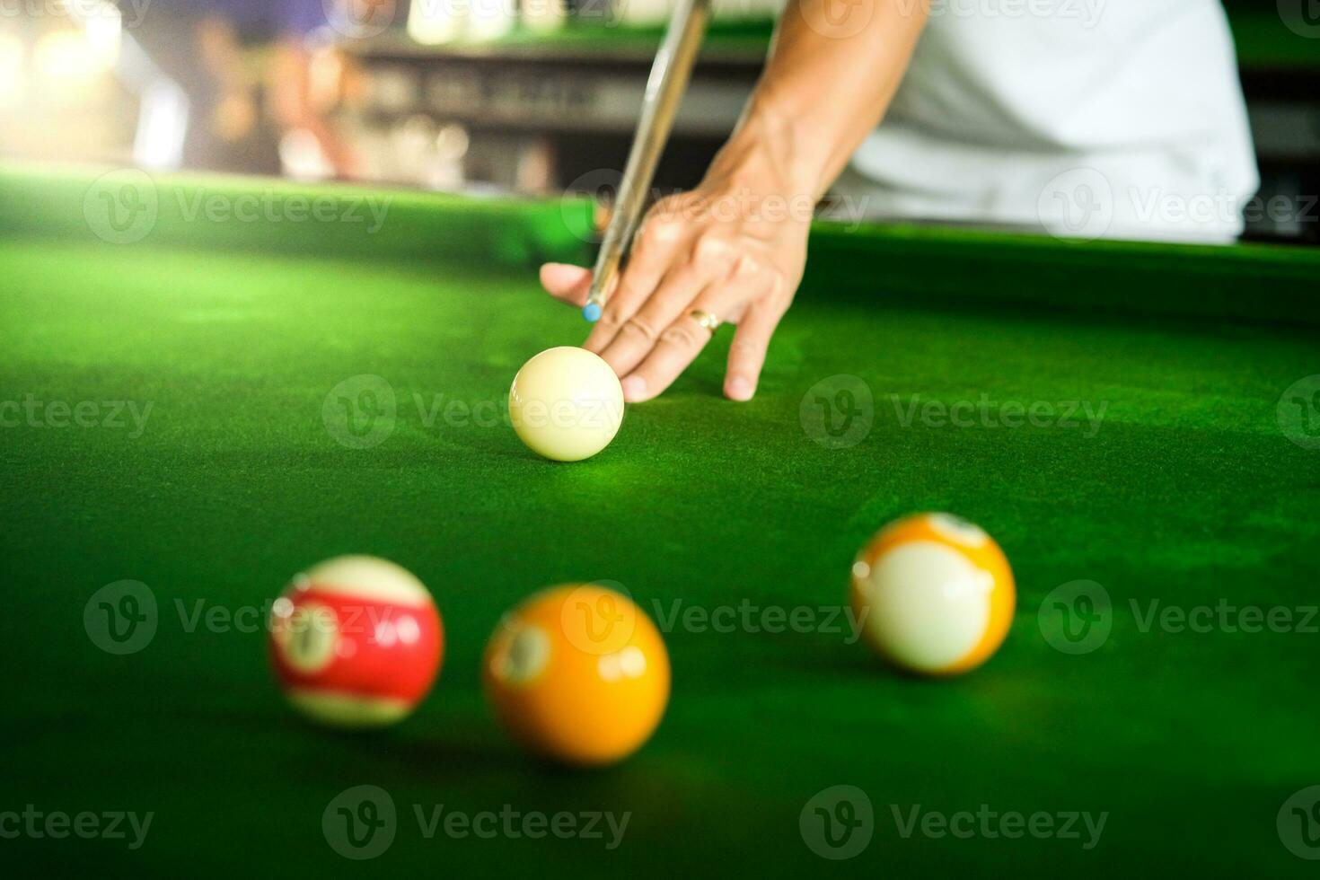 Man's hand and Cue arm playing snooker game or preparing aiming to shoot pool balls on a green billiard table. Colorful snooker balls on green frieze. photo