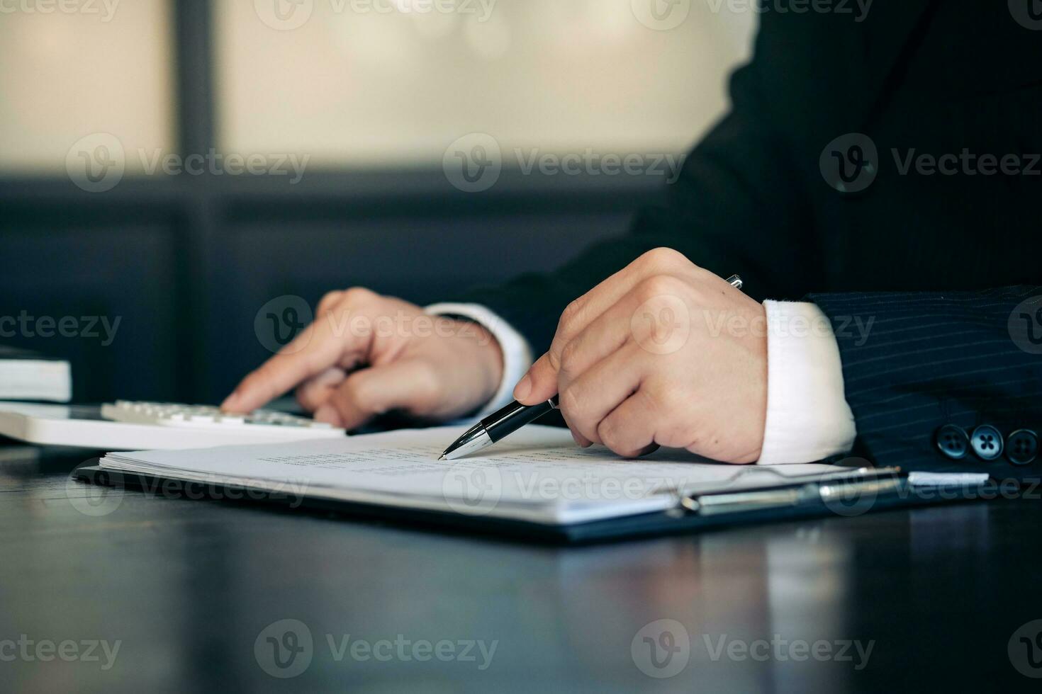Businessman analyzing investment charts and pressing calculator buttons over documents. Accounting Concept. photo