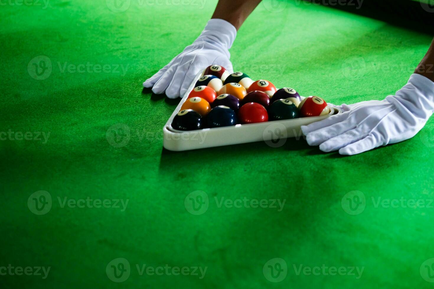 Man's hand and Cue arm playing snooker game or preparing aiming to shoot pool balls on a green billiard table. Colorful snooker balls on green frieze. photo