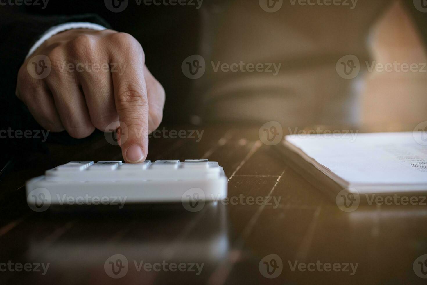 Businessman analyzing investment charts and pressing calculator buttons over documents. Accounting Concept. photo