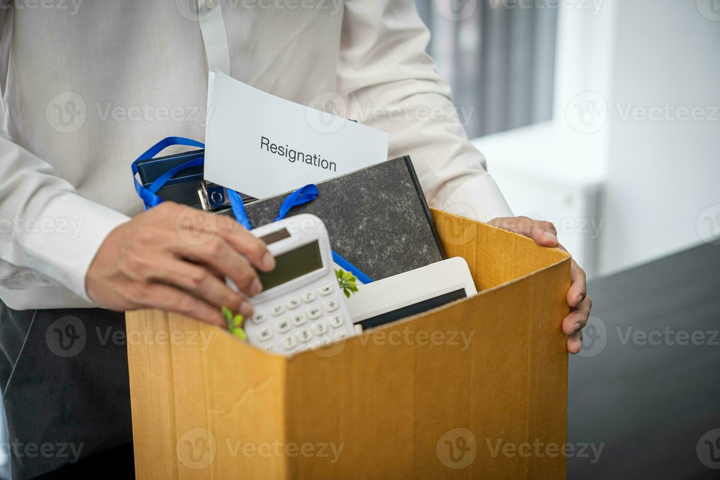 Business man sending resignation letter and packing Stuff Resign Depress or carrying business cardboard box by desk in office. Change of job or fired from company photo