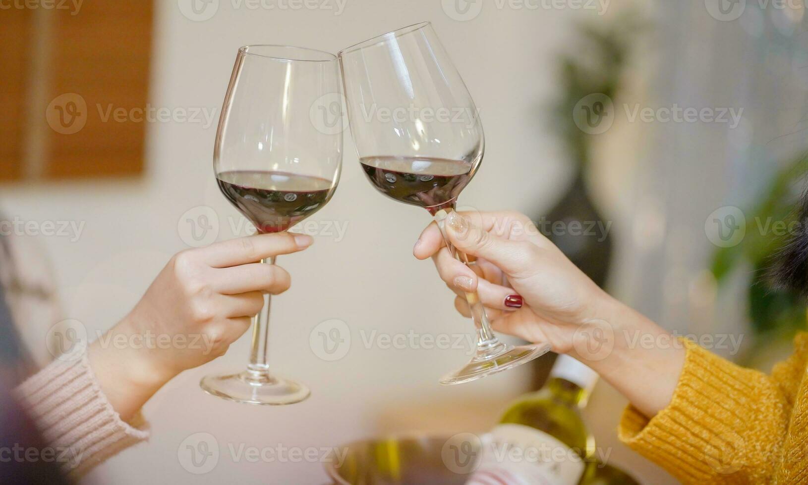 Cheerful friends enjoying home Birthday holiday party. Asian Friends cheering drinking red wine celebrating Christmas or New Year party photo