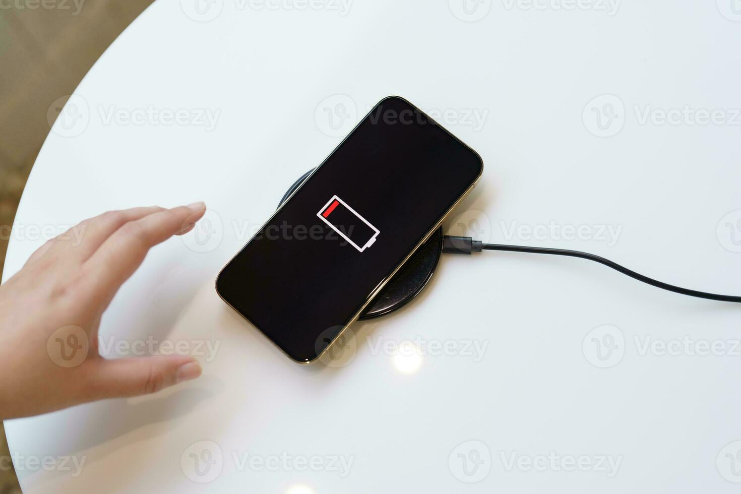 Charging mobile phone battery with wireless charging device in the table. Smartphone charging on a charging pad. Mobile phone near wireless charger Modern lifestyle technology concept. photo