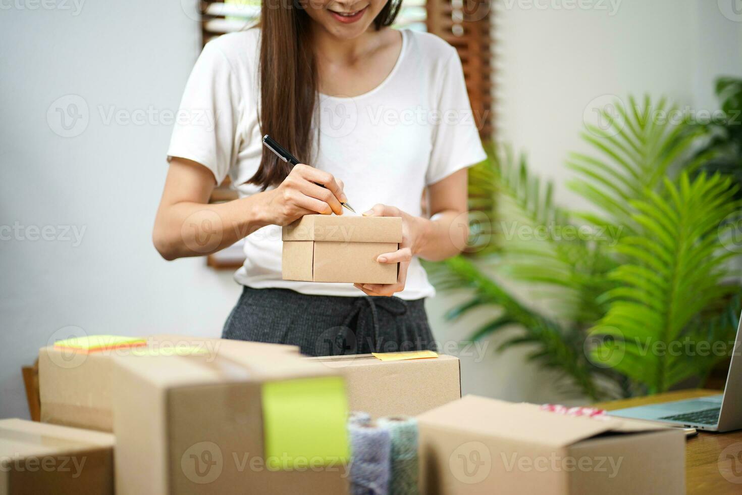 Business From Home Asian woman preparing package delivery box Shipping for shopping online. young start up small business owner at home online order photo