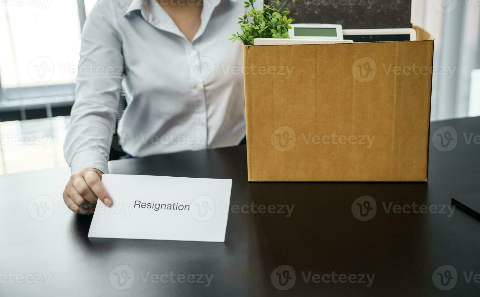 Business woman sending resignation letter to boss and Holding Stuff Resign Depress or carrying cardboard box by desk in office photo