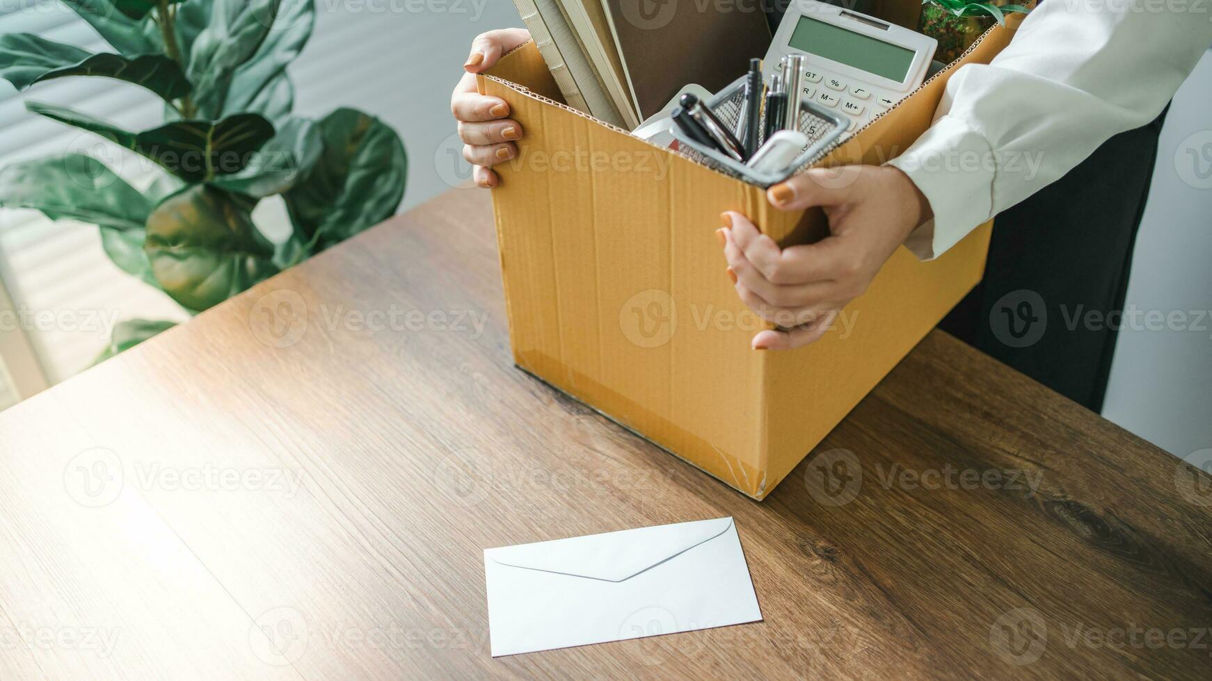 Business woman sending resignation letter and packing Stuff Resign Depress or carrying business cardboard box by desk in office. Change of job or fired from company photo