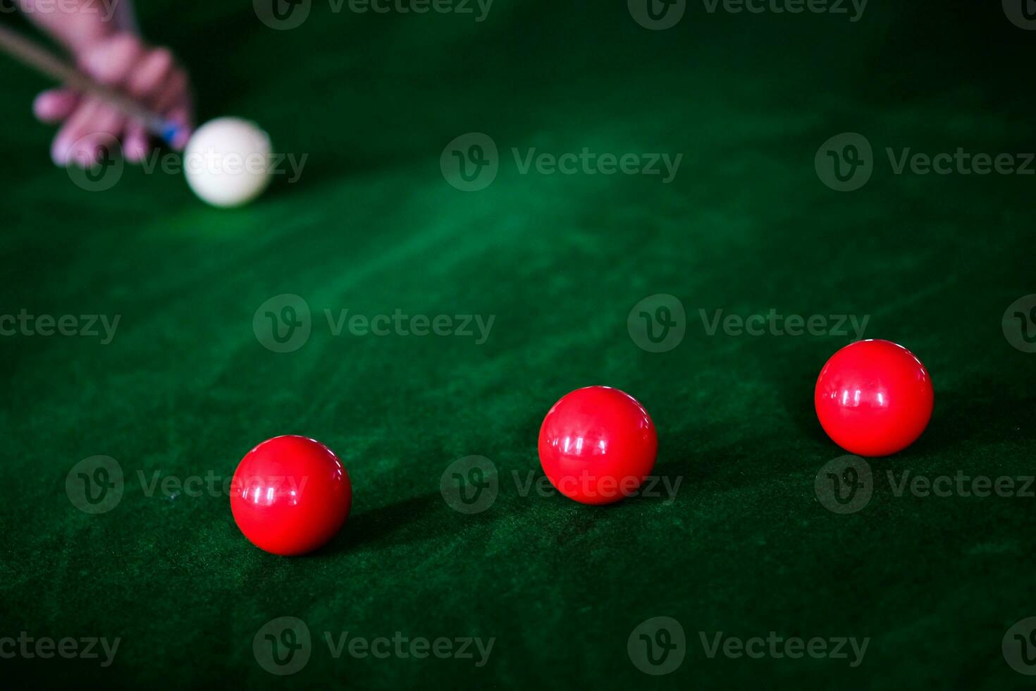 Man's hand and Cue arm playing snooker game or preparing aiming to shoot pool balls on a green billiard table. Colorful snooker balls on green frieze. photo