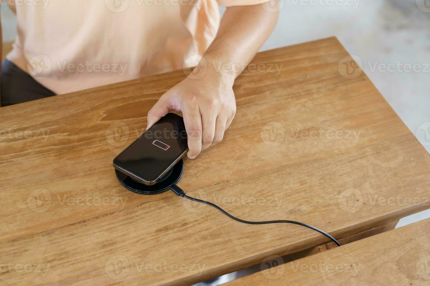 Charging mobile phone battery with wireless charging device in the table. Smartphone charging on a charging pad. Mobile phone near wireless charger Modern lifestyle technology concept. photo