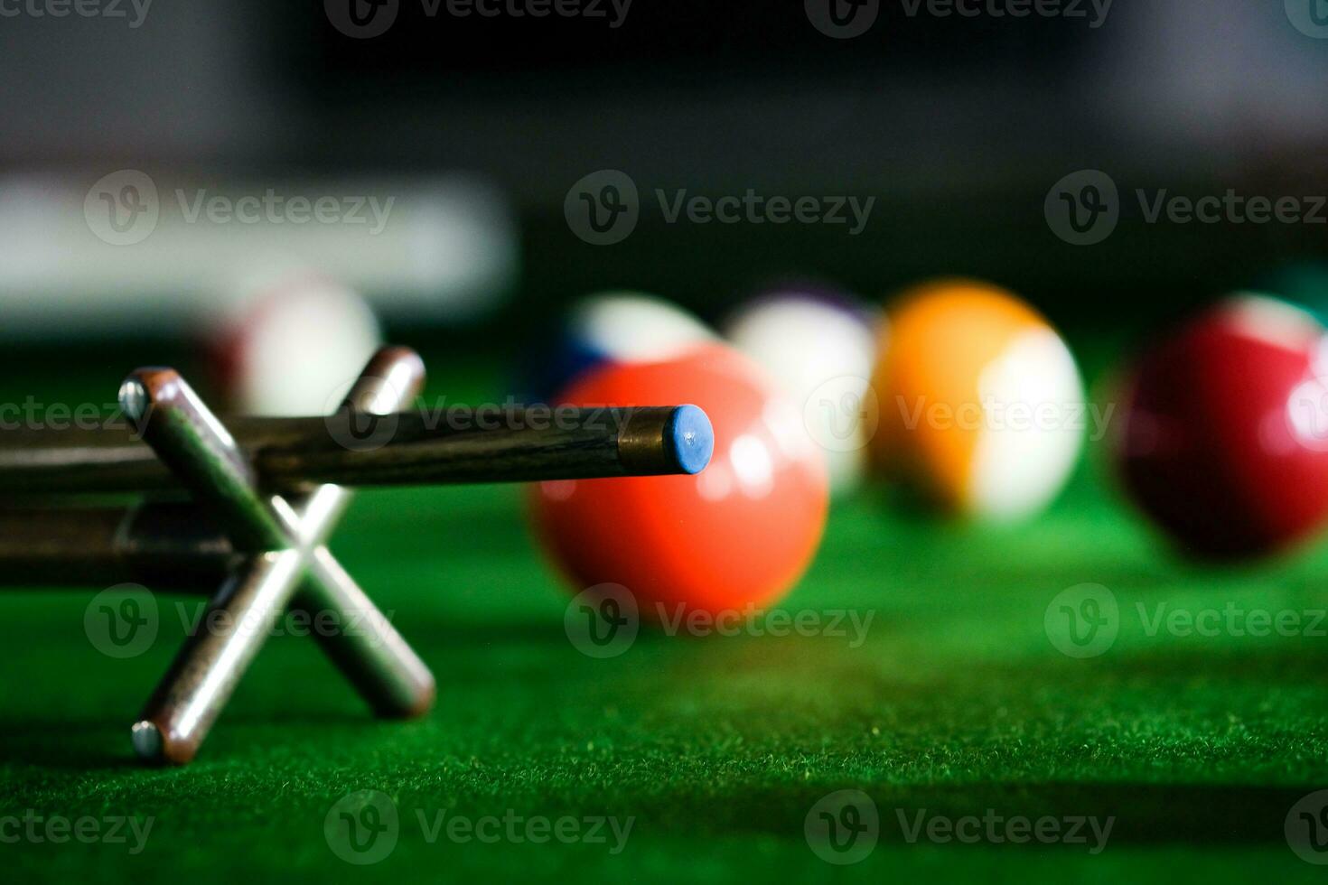 Man's hand and Cue arm playing snooker game or preparing aiming to shoot pool balls on a green billiard table. Colorful snooker balls on green frieze. photo