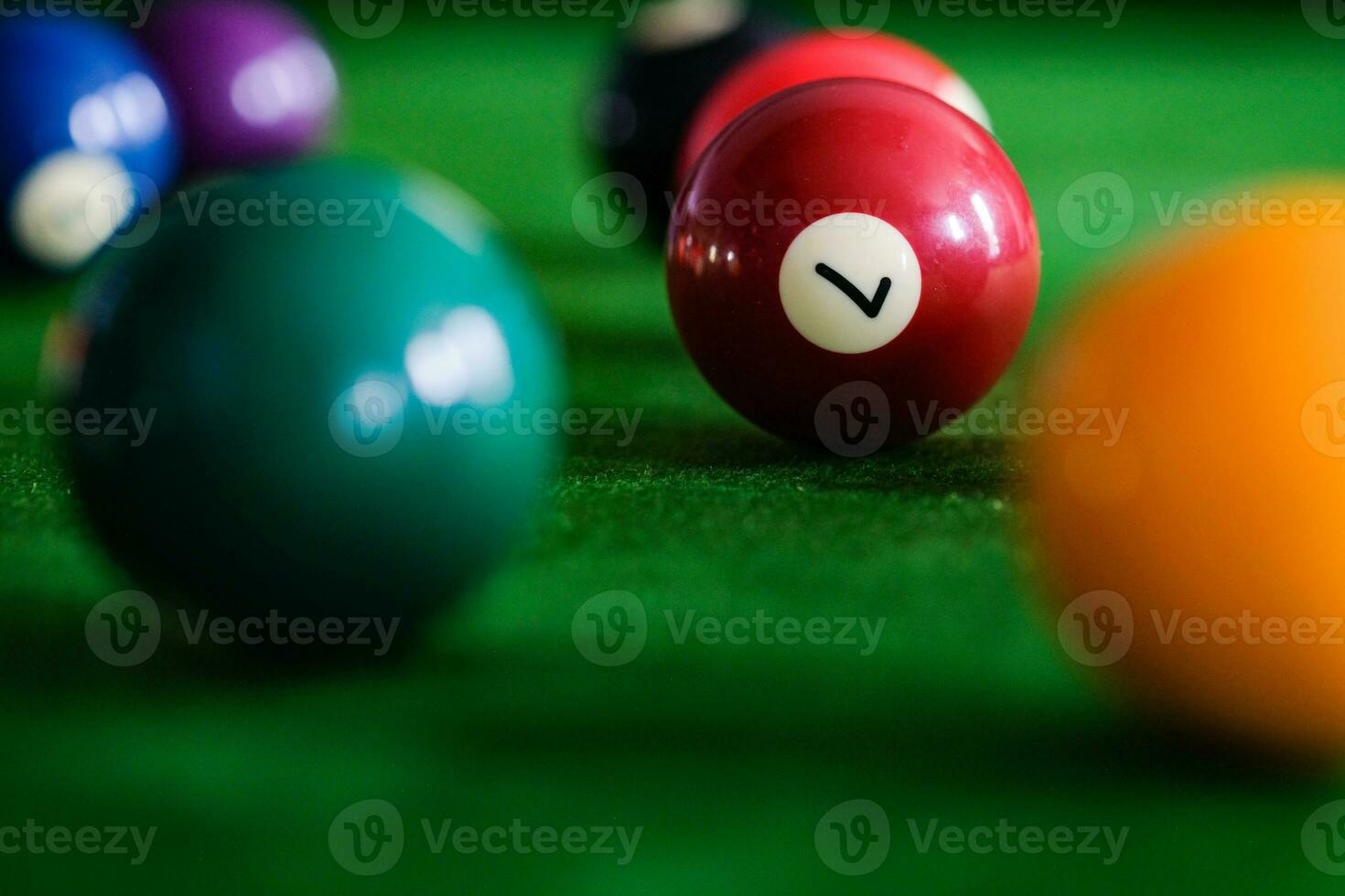 Man's hand and Cue arm playing snooker game or preparing aiming to shoot pool balls on a green billiard table. Colorful snooker balls on green frieze. photo