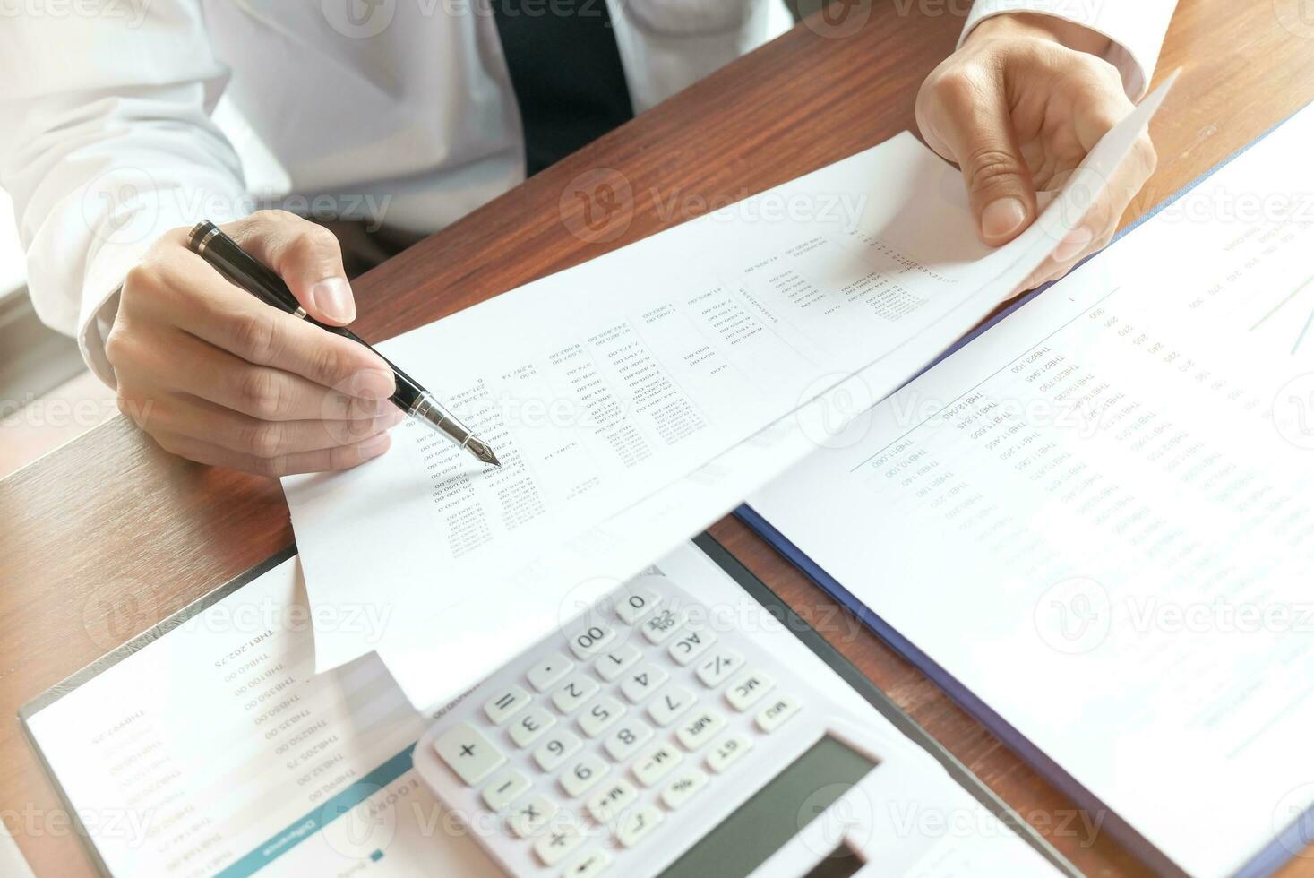 Businessman analyzing investment charts and pressing calculator buttons over documents. Accounting Concept. photo