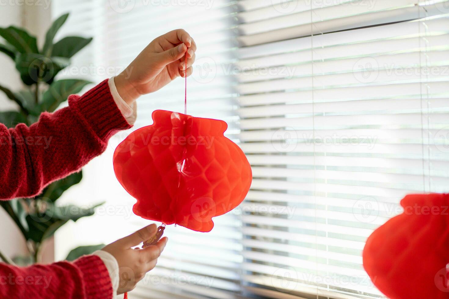 Asian Woman holding red Chinese new year lantern while decorated flat putting traditional pendant to the Chinese New Year Celebrations for good luck. chinese word means blessing. photo