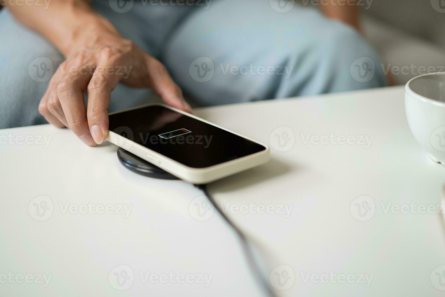 Charging mobile phone battery with wireless charging device in the table. Smartphone charging on a charging pad. Mobile phone near wireless charger Modern lifestyle technology concept. photo