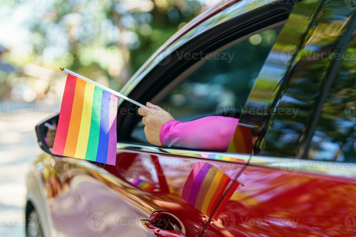 Happy Asian woman support LGBT pride parade in car. with Rainbow of LGBTQ or LGBTQIA. photo