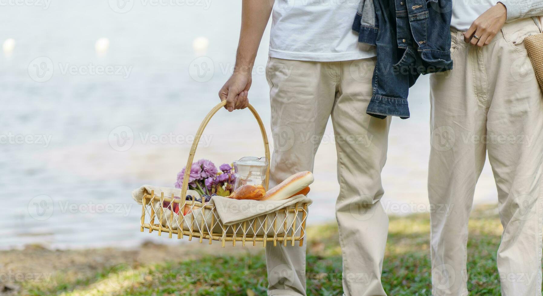 Pareja caminando en jardín con picnic cesta. en amor Pareja es disfrutando picnic hora en parque al aire libre foto