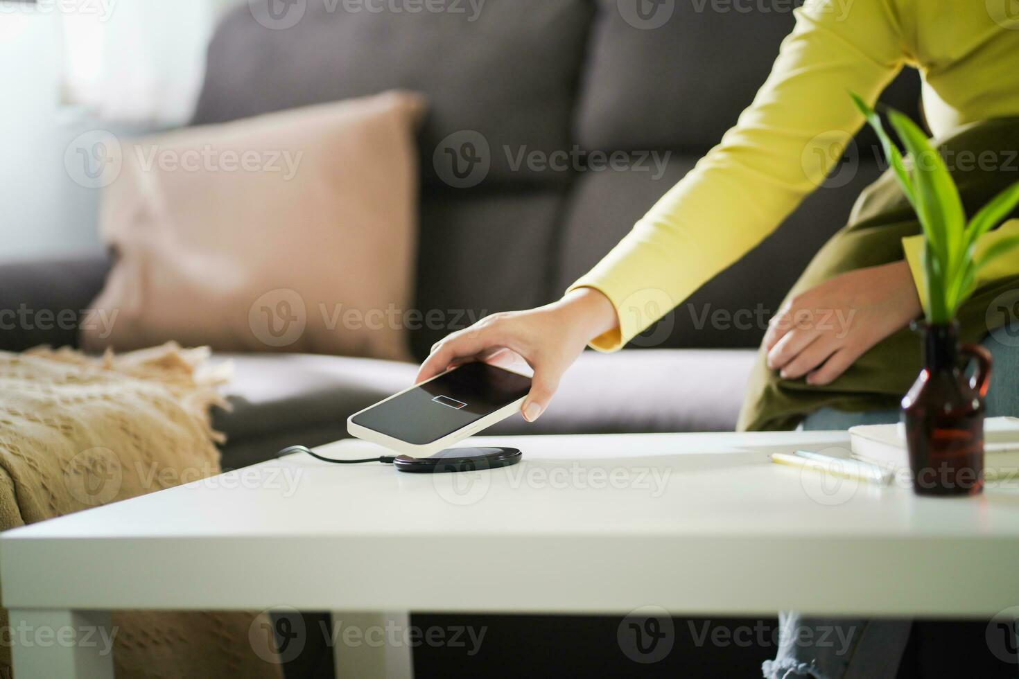 Charging mobile phone battery with wireless charging device in the table. Smartphone charging on a charging pad. Mobile phone near wireless charger Modern lifestyle technology concept. photo