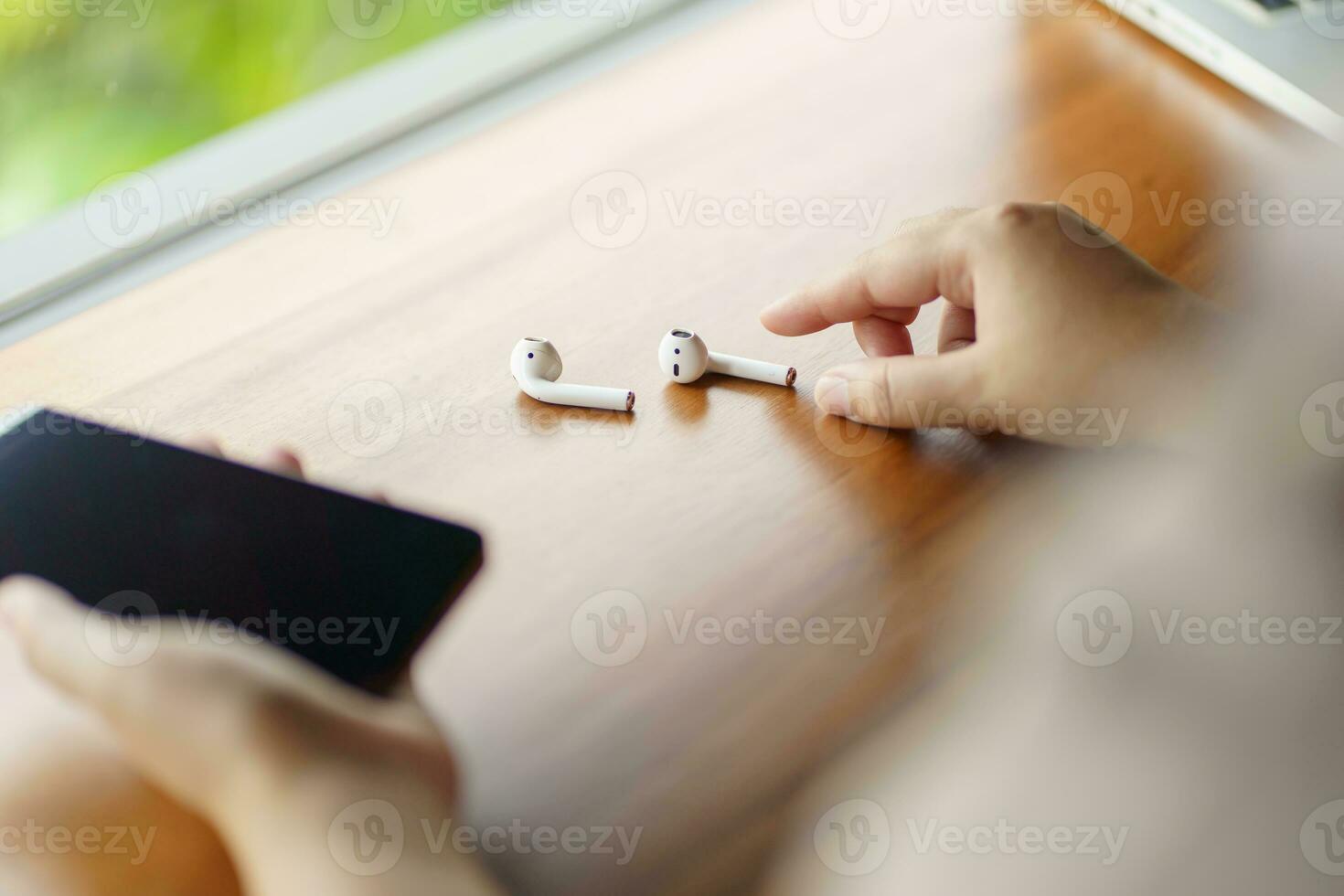 woman takes out wireless bluetooth headphones. earphones using smartphone photo