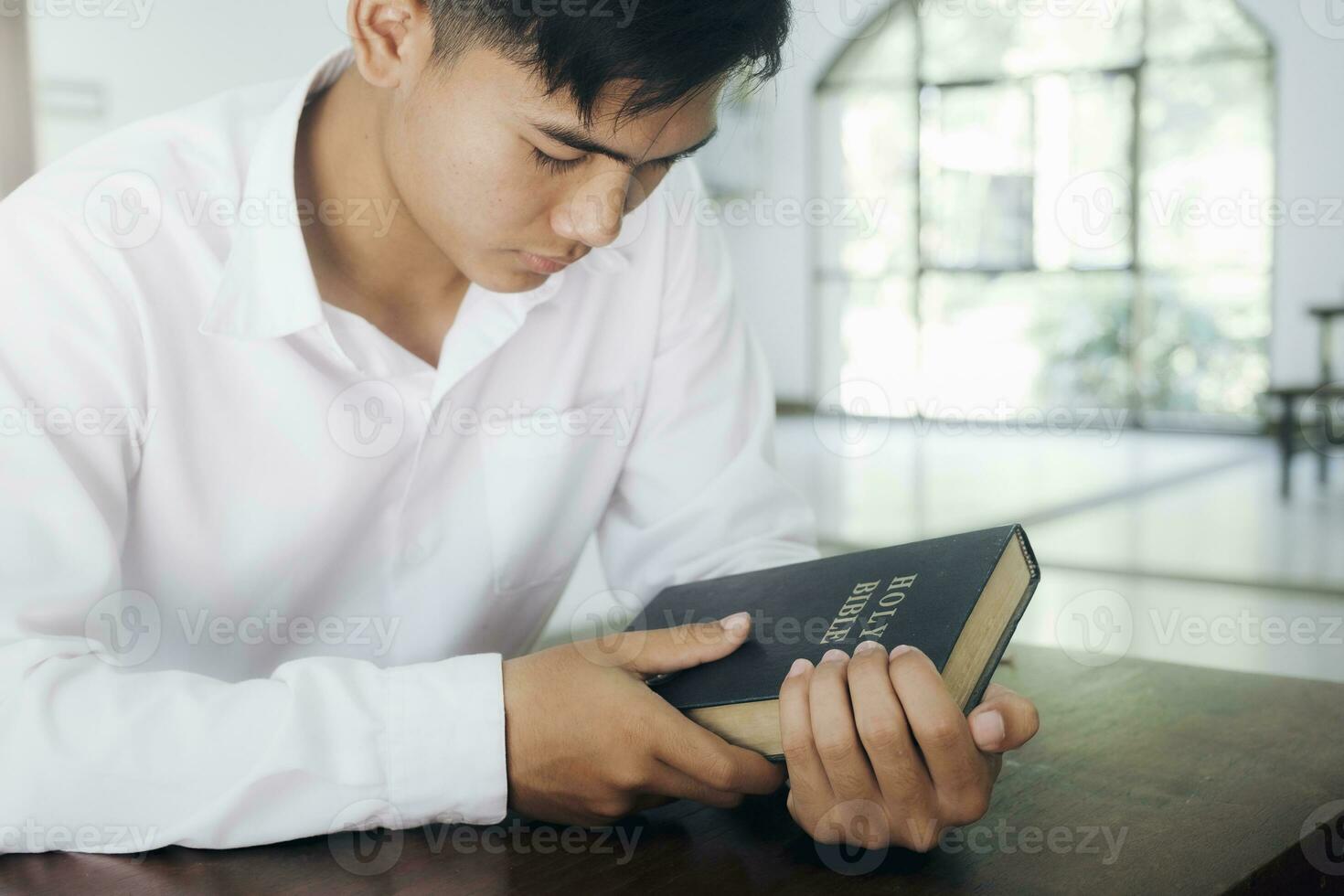 Man praying, hands clasped together on her Bible. photo
