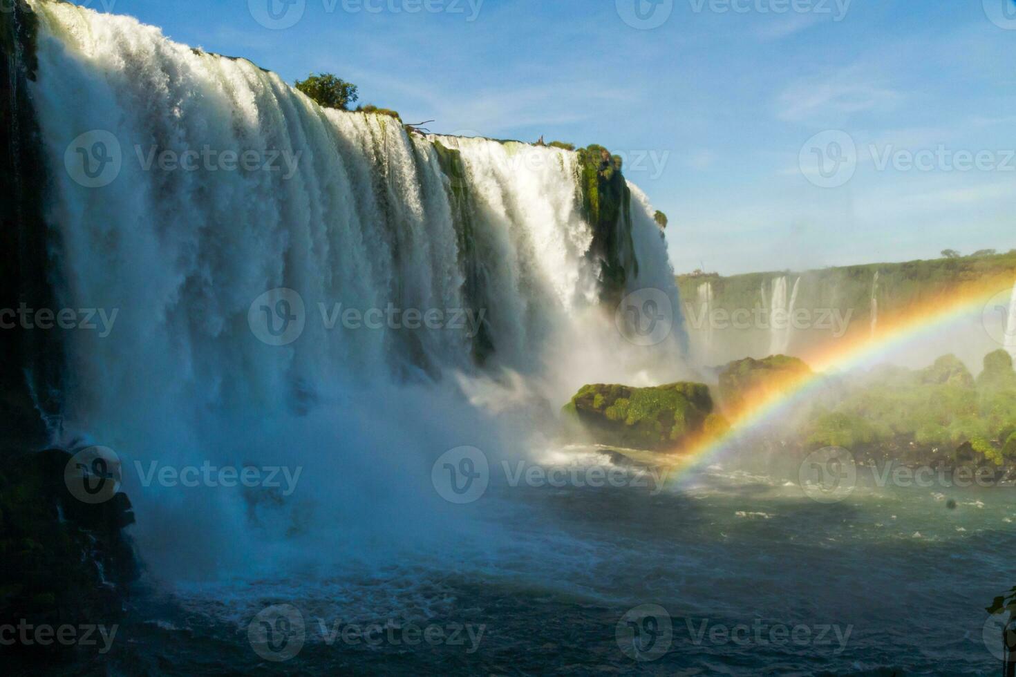 Iguazu Falls on the border between Argentina and Brazil with beautiful rainbows and lots of vegetation and lots of water falling down them photo